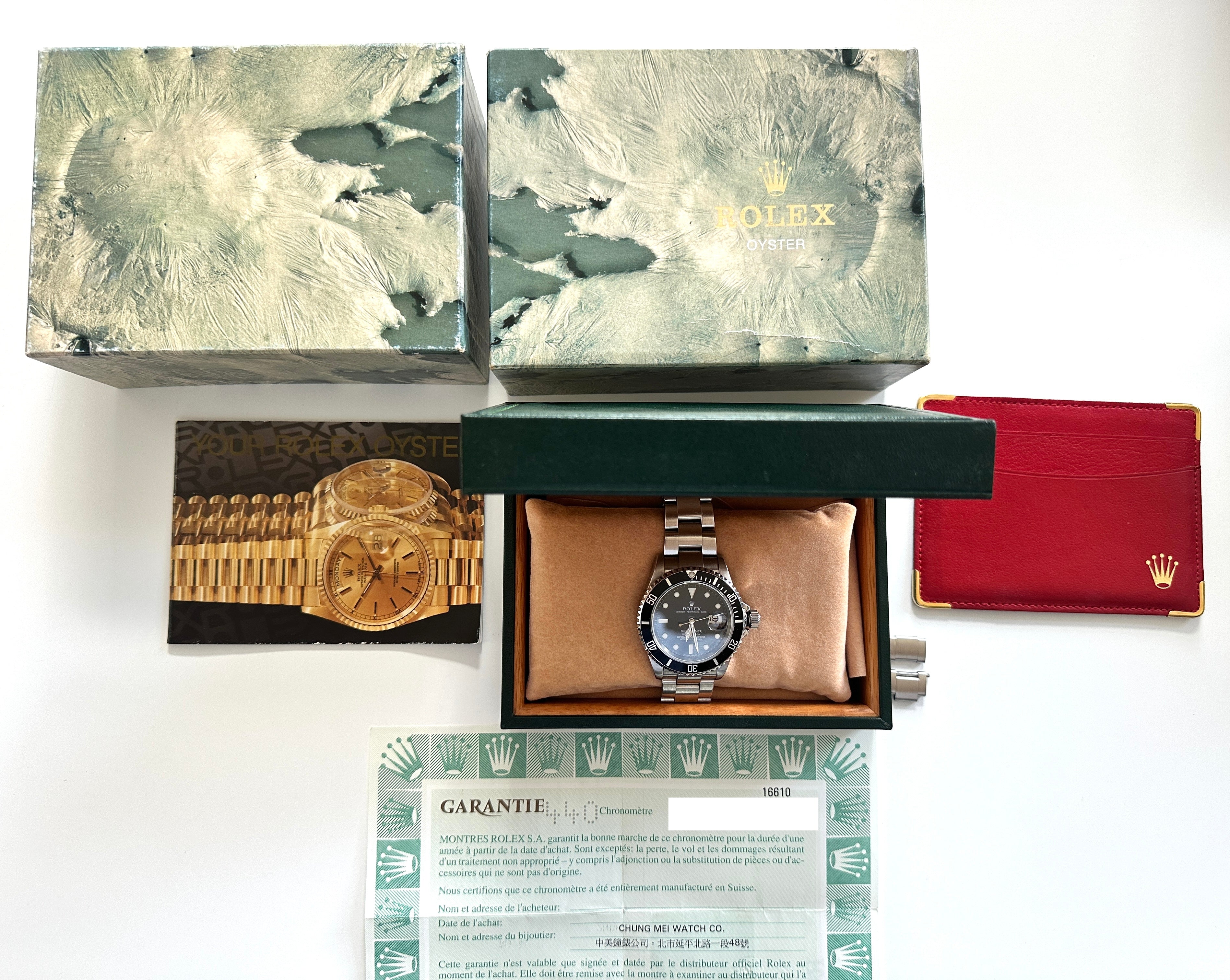 Rolex Submariner Date 16610 Uhr in OVP mit Papieren auf hellem Hintergrund