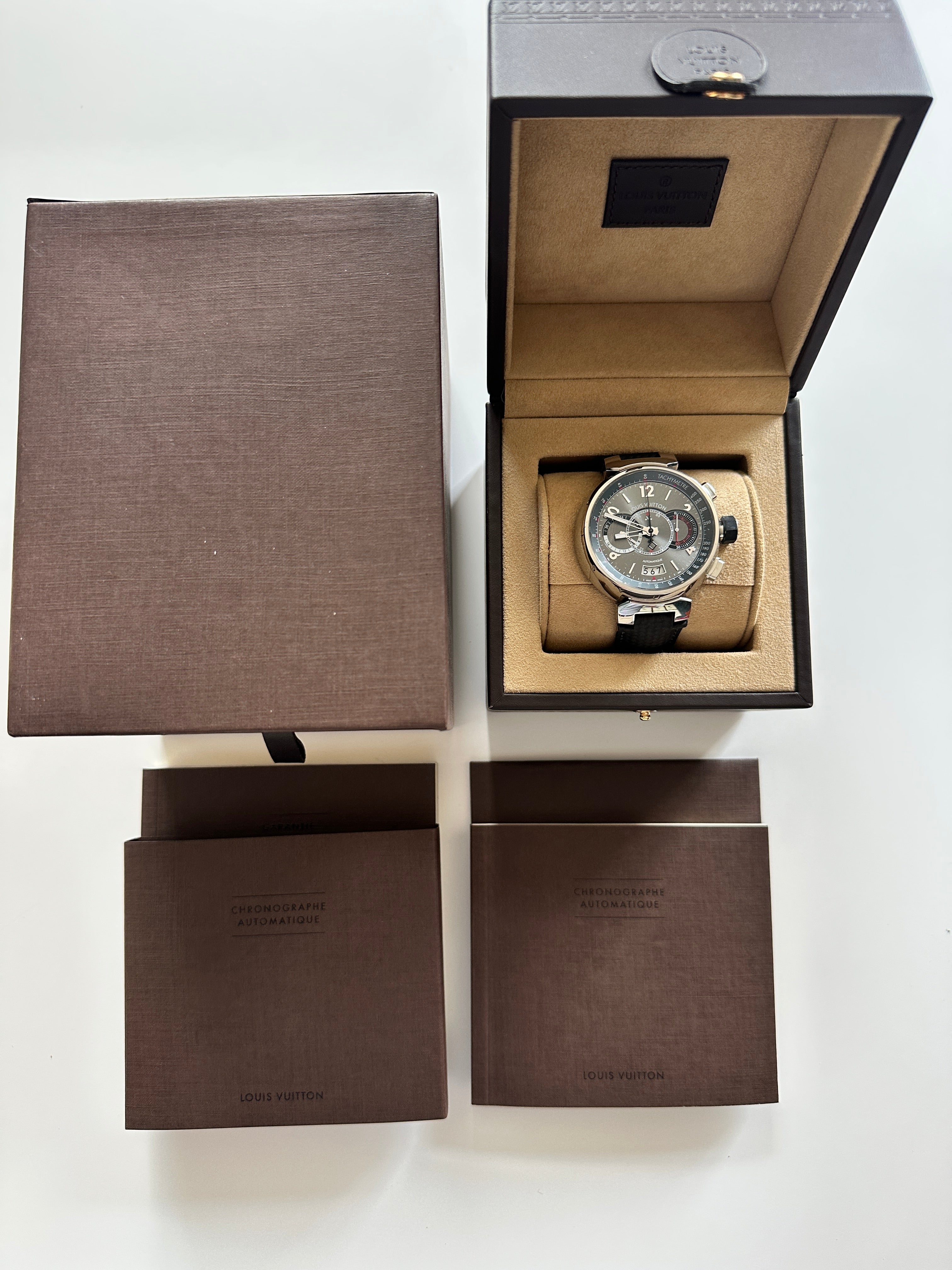Louis Vuitton Tambour Chronograph in geöffneter brauner Box mit Bedienungsanleitungen auf weißem Hintergrund