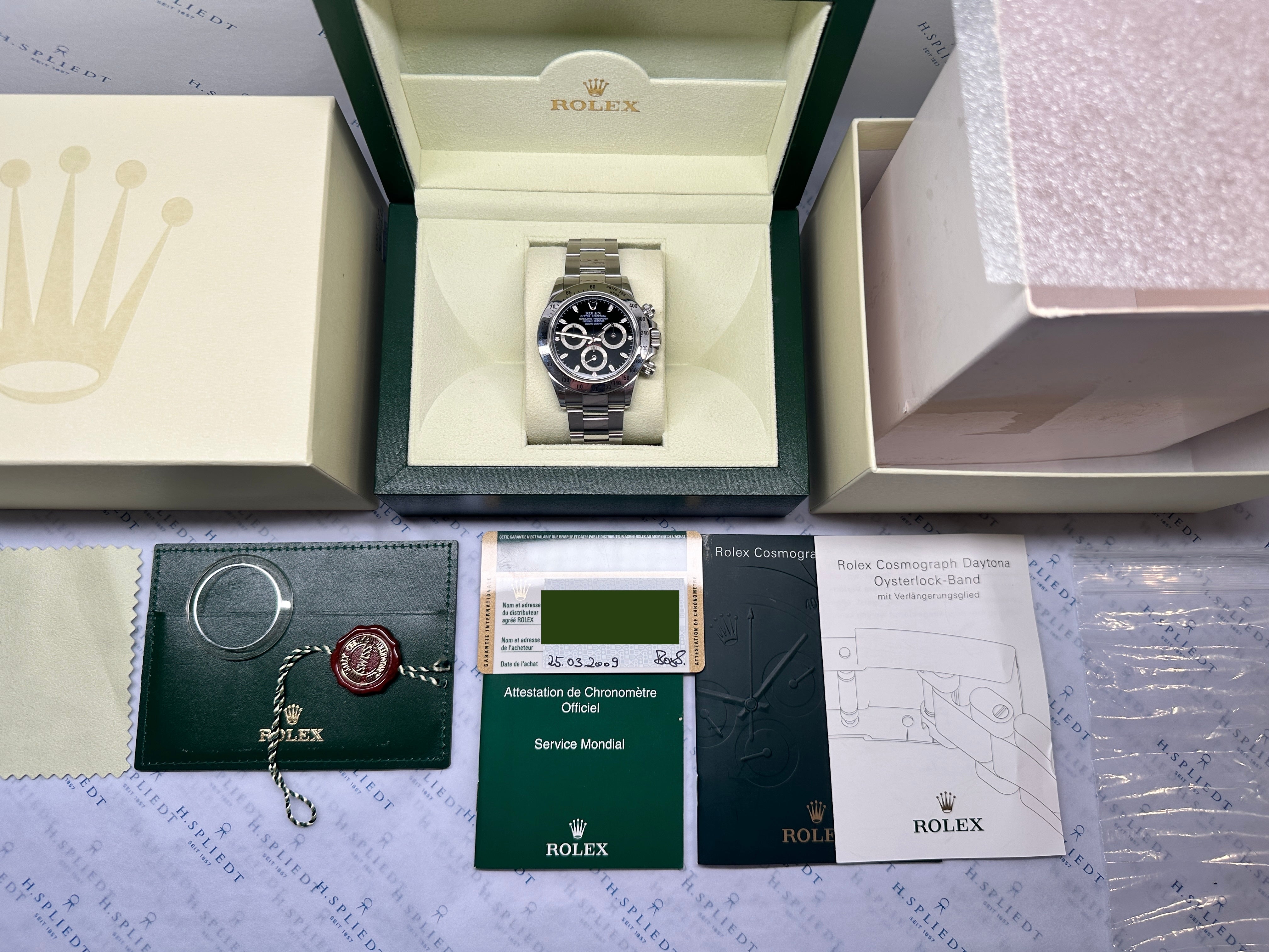 Rolex Daytona 116520 im geöffneten Kasten auf dem Original-Zubehör, mit Papieren und Siegel