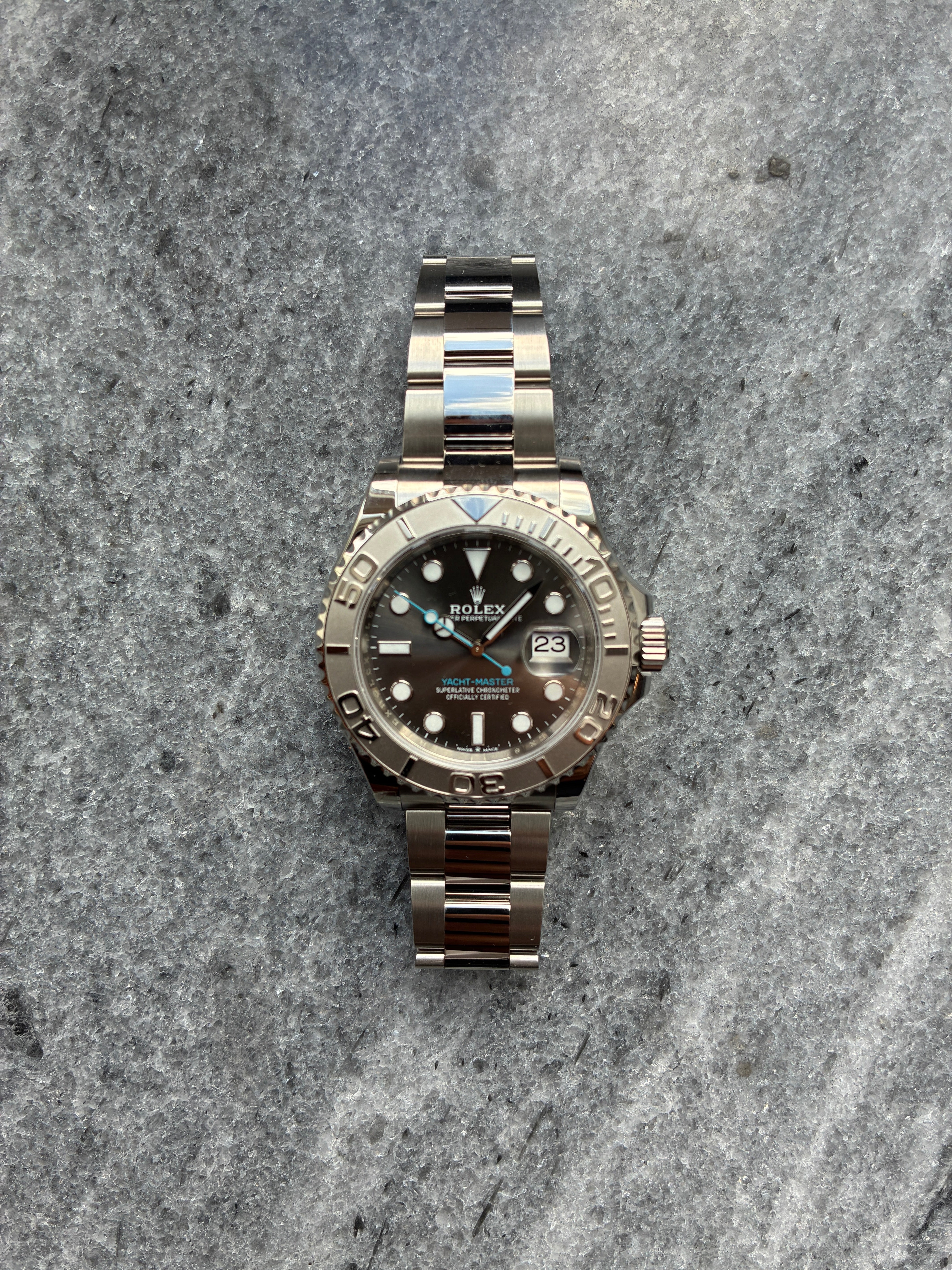Rolex Yacht-Master 40 mit Rhodium-Zifferblatt, Edelstahlgehäuse und Automatikwerk auf strukturiertem grauem Hintergrund