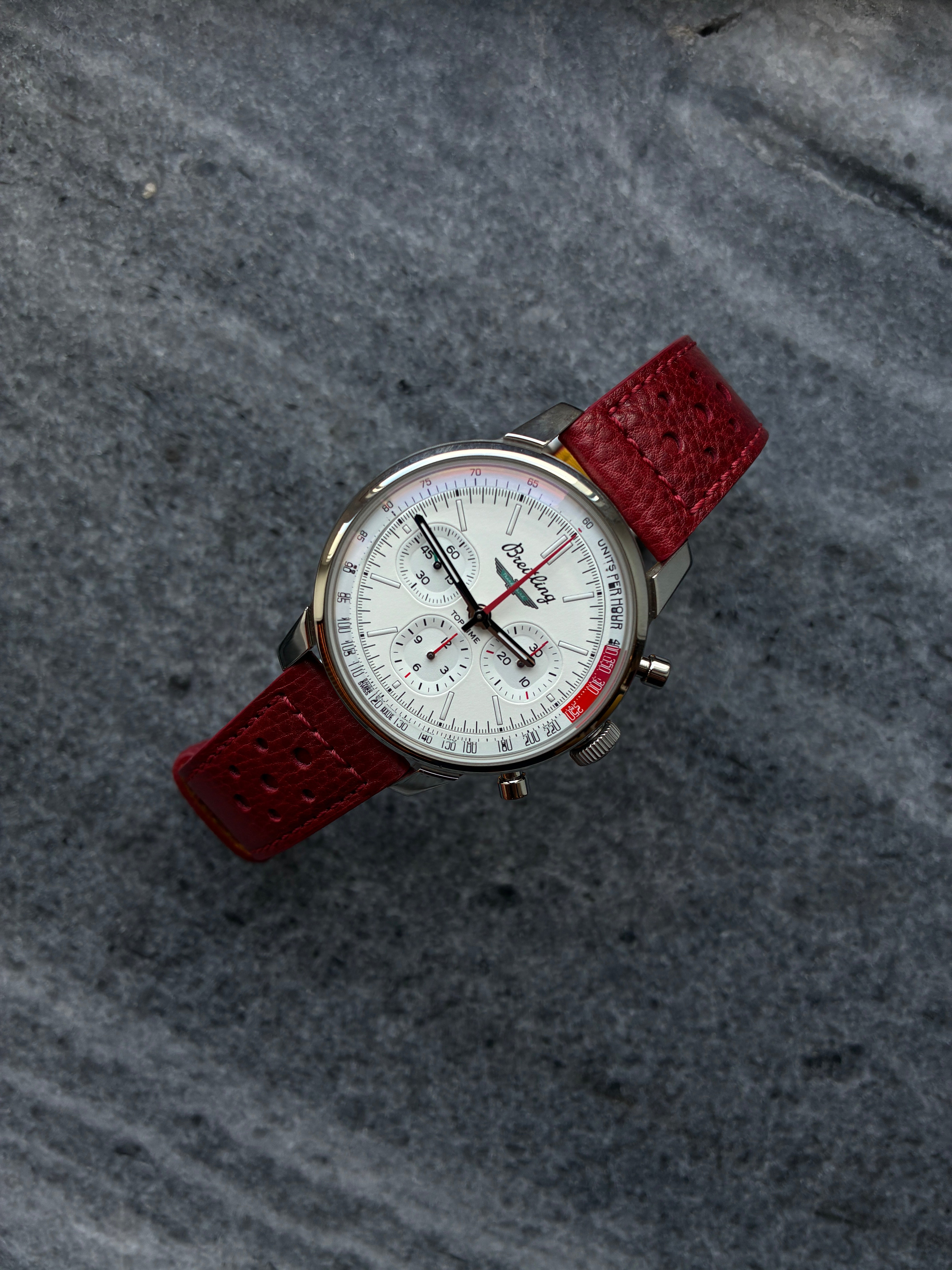 Breitling Top Time B01 Ford Thunderbird Automatik mit weißem Zifferblatt und rotem Lederarmband auf Steingrund