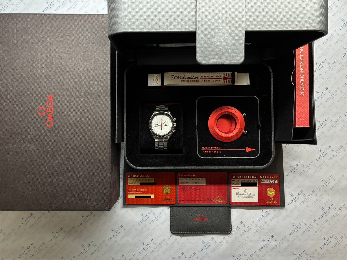 Omega Speedmaster Professional Moonwatch Alaska Project / Limited Edition / very rare / Full-Set / 2008, Gesamtansicht mit Box, Unterlagen und Zifferblatt vor neutralem Hintergrund