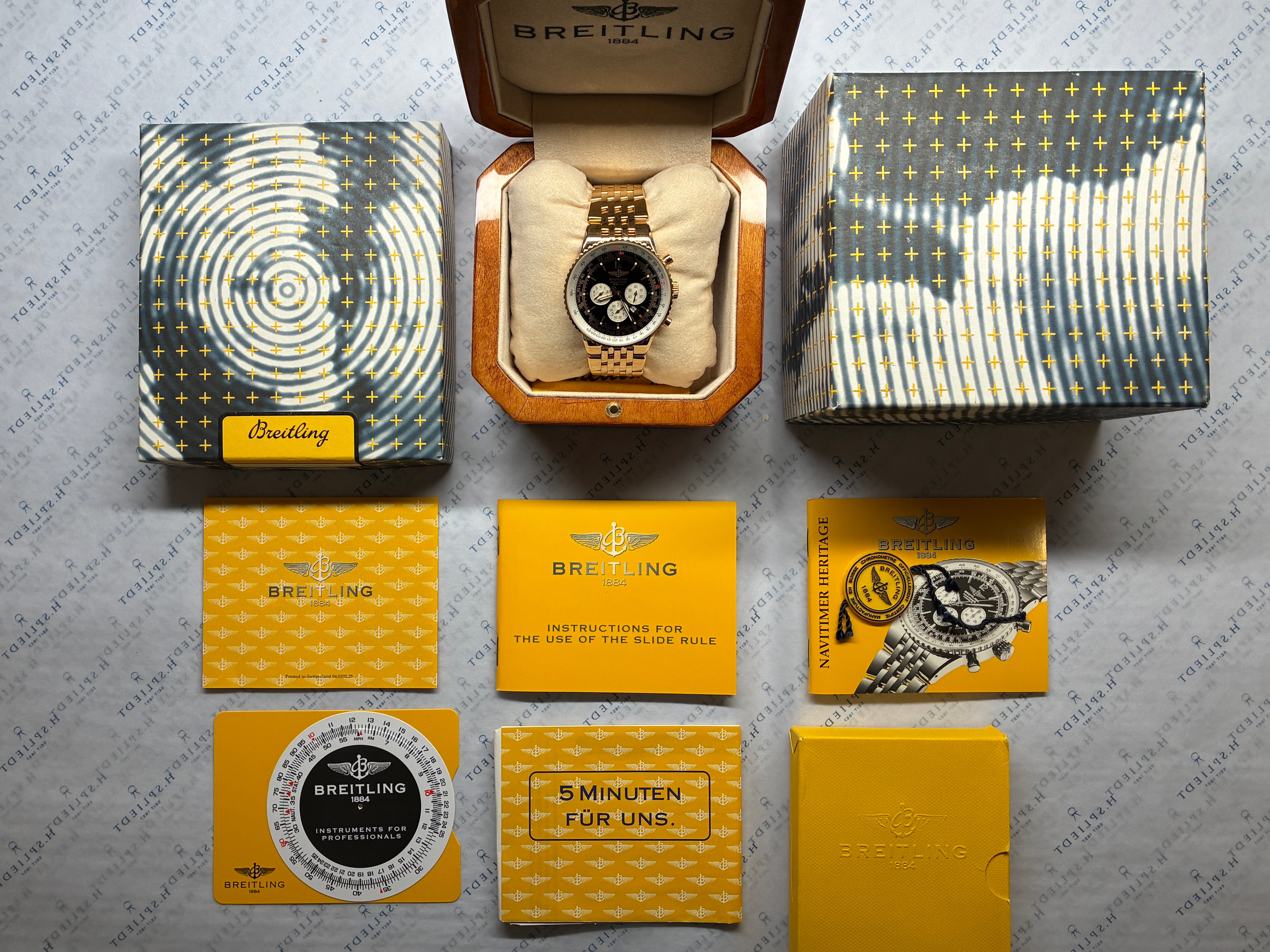 Breitling Navitimer Heritage in Gold im Karton mit Dokumenten auf Hintergrund mit Logo