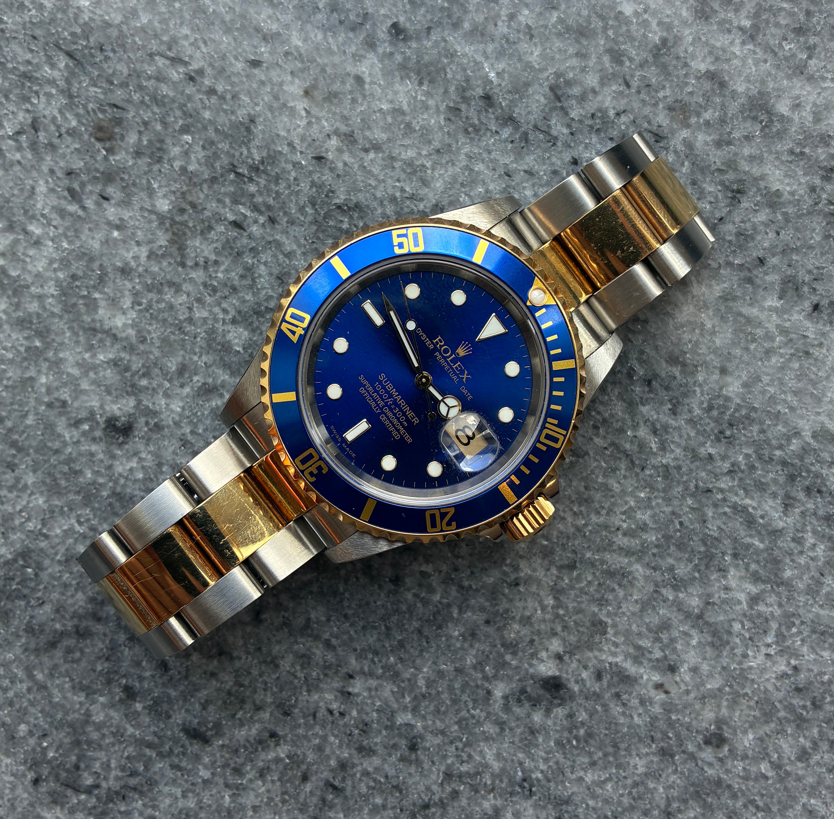 Rolex Submariner Date Bicolor Uhr auf grauem Untergrund, zwei Zeiger, ein Datumsfenster