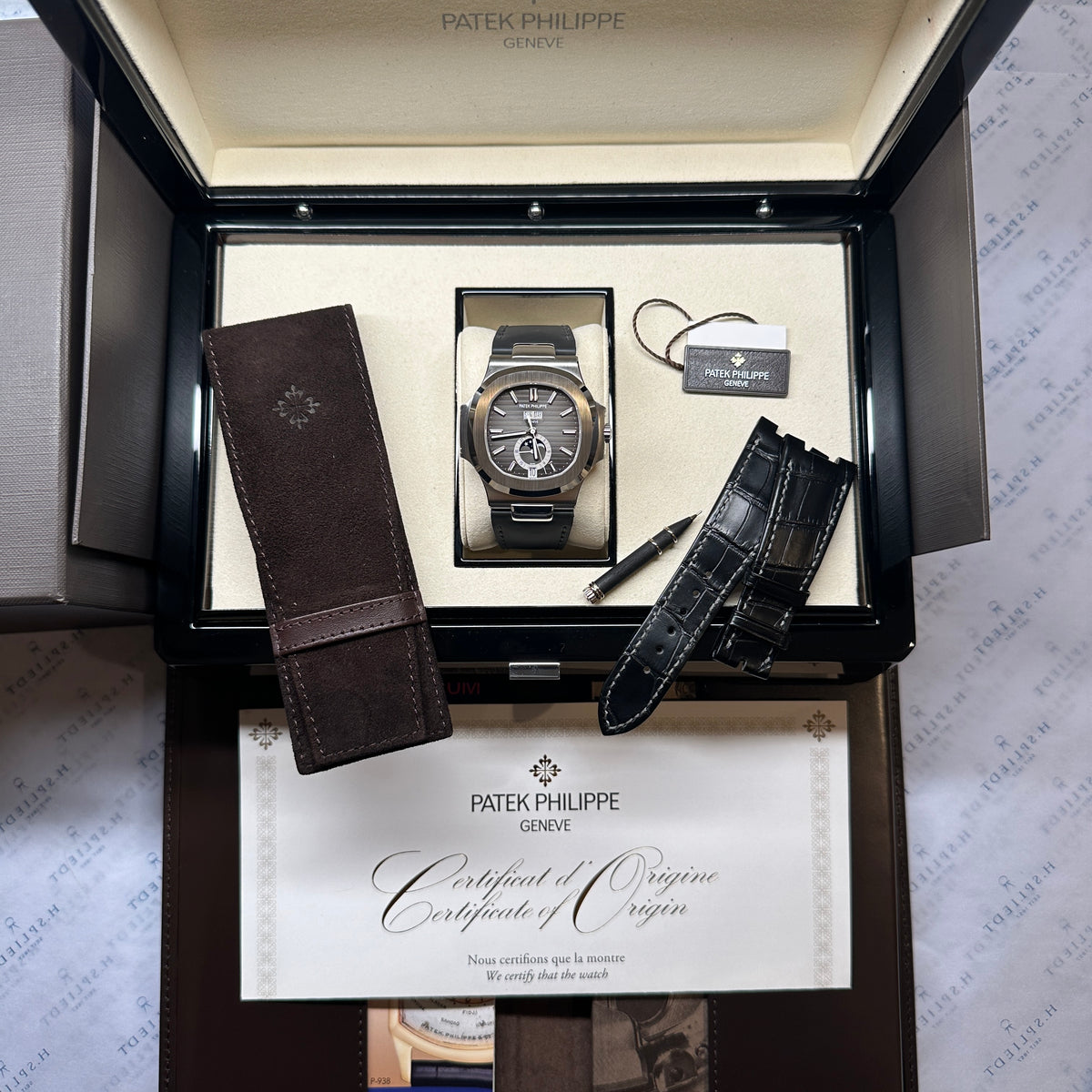 Patek Philippe Nautilus Annual Calendar 5726A-001 / premium Condition / Full Set / second Strap / Germany / 2025, Gesamtansicht mit Box, Zifferblatt und Armband vor neutralem Hintergrund