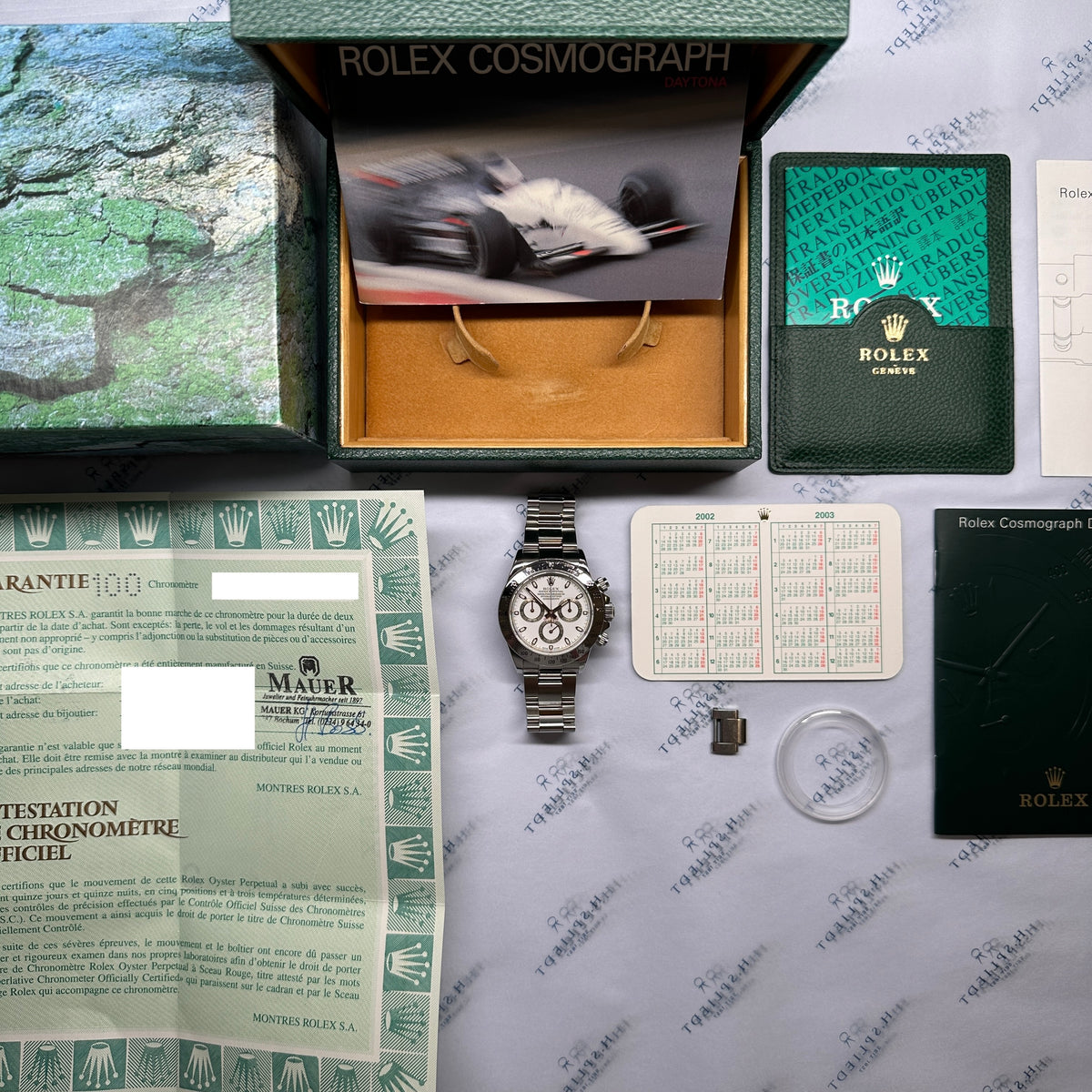 Rolex Daytona white Dial 116520 / very good Condition / Full Set / LC100 / 2002, Gesamtansicht mit Box, Unterlagen und Zifferblatt vor neutralem Hintergrund