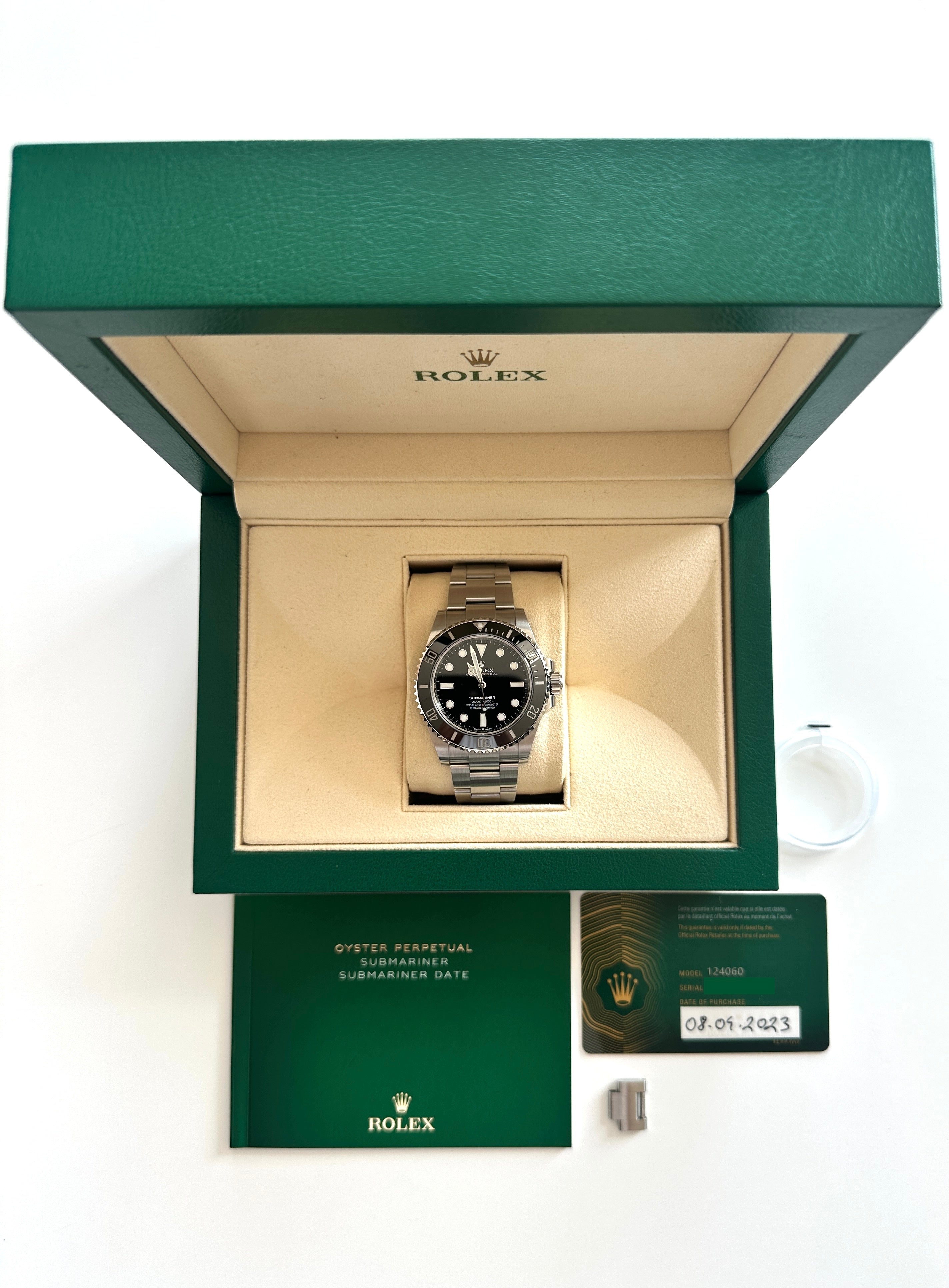 Rolex Submariner 124060 im grünen Karton mit Papieren auf weißem Hintergrund