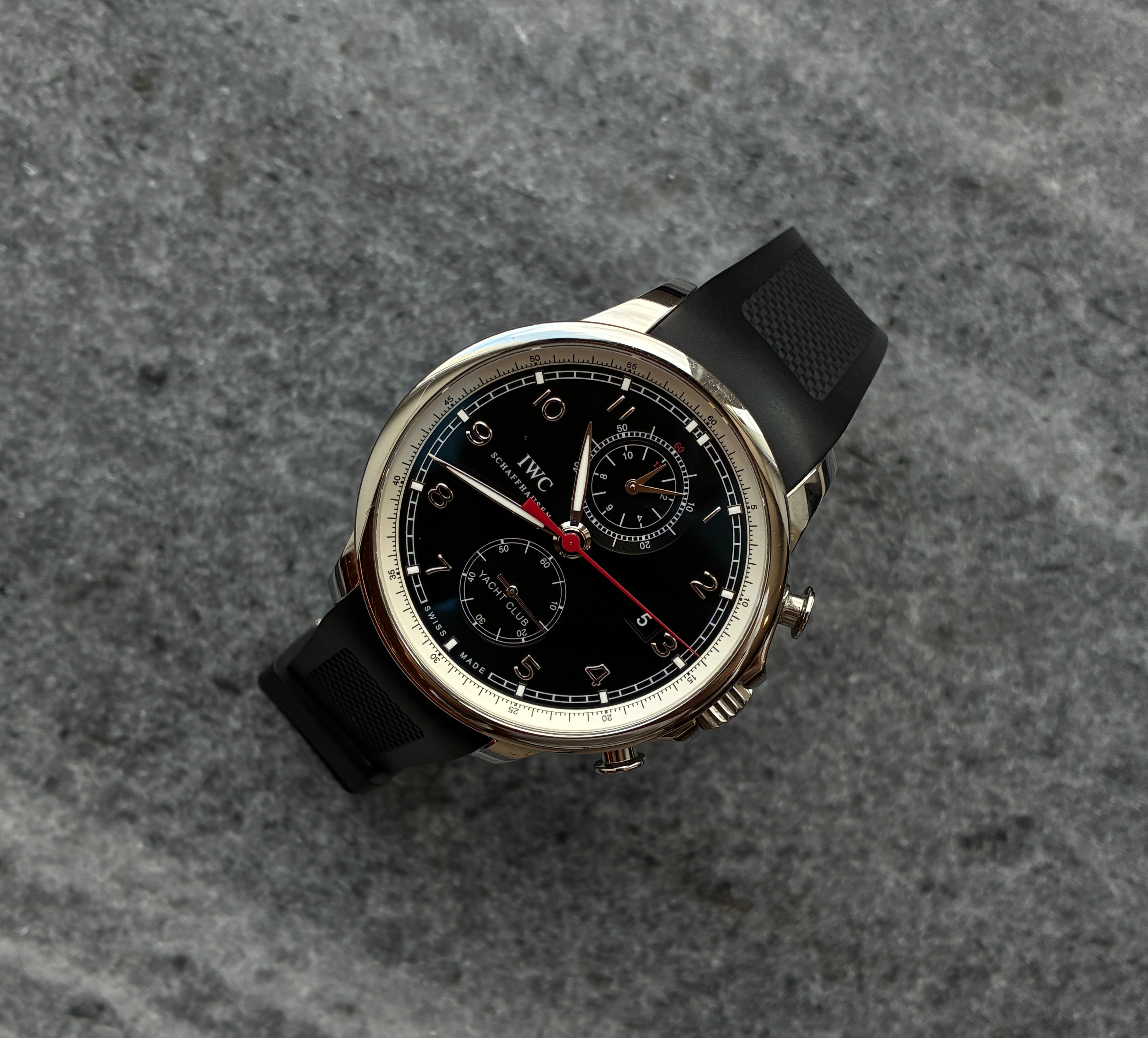 IWC Portuguese Yacht Club Chronograph aus Edelstahl mit schwarzem Zifferblatt und Kautschukband auf Steingrund