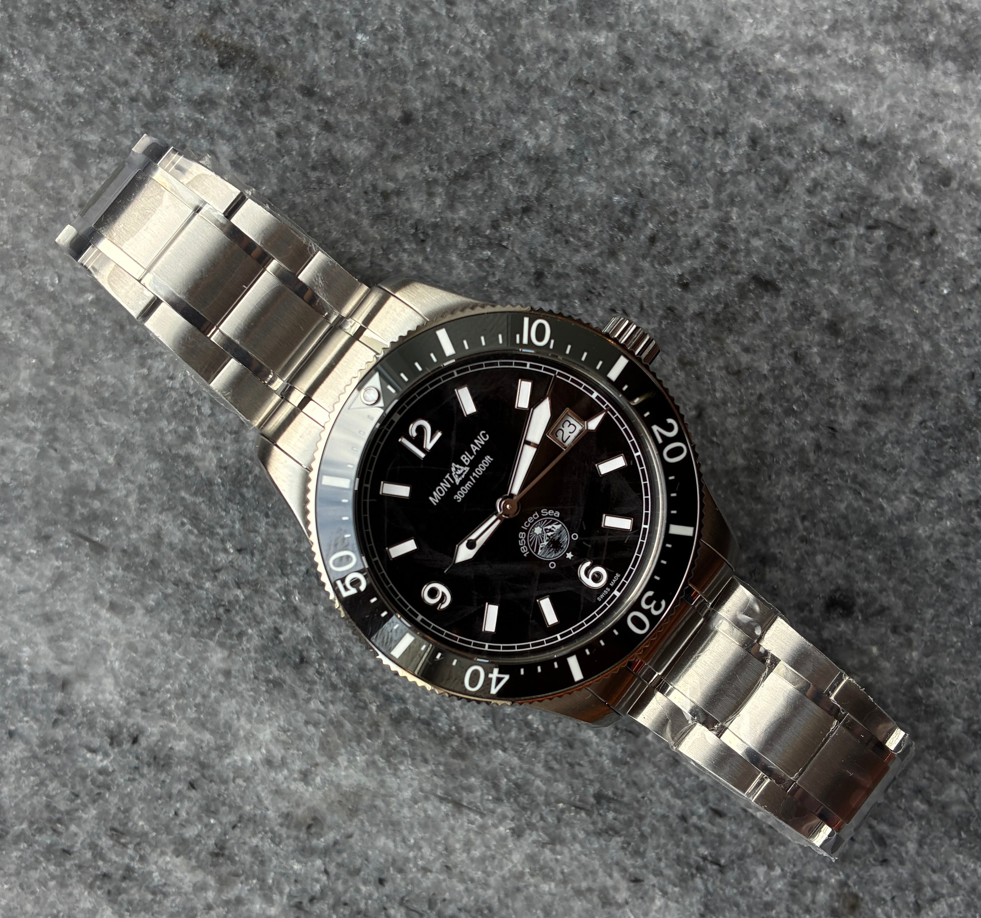 Montblanc 1858 Iced Sea Automatik mit schwarzem Zifferblatt und Edelstahlarmband auf grauer Steintextur