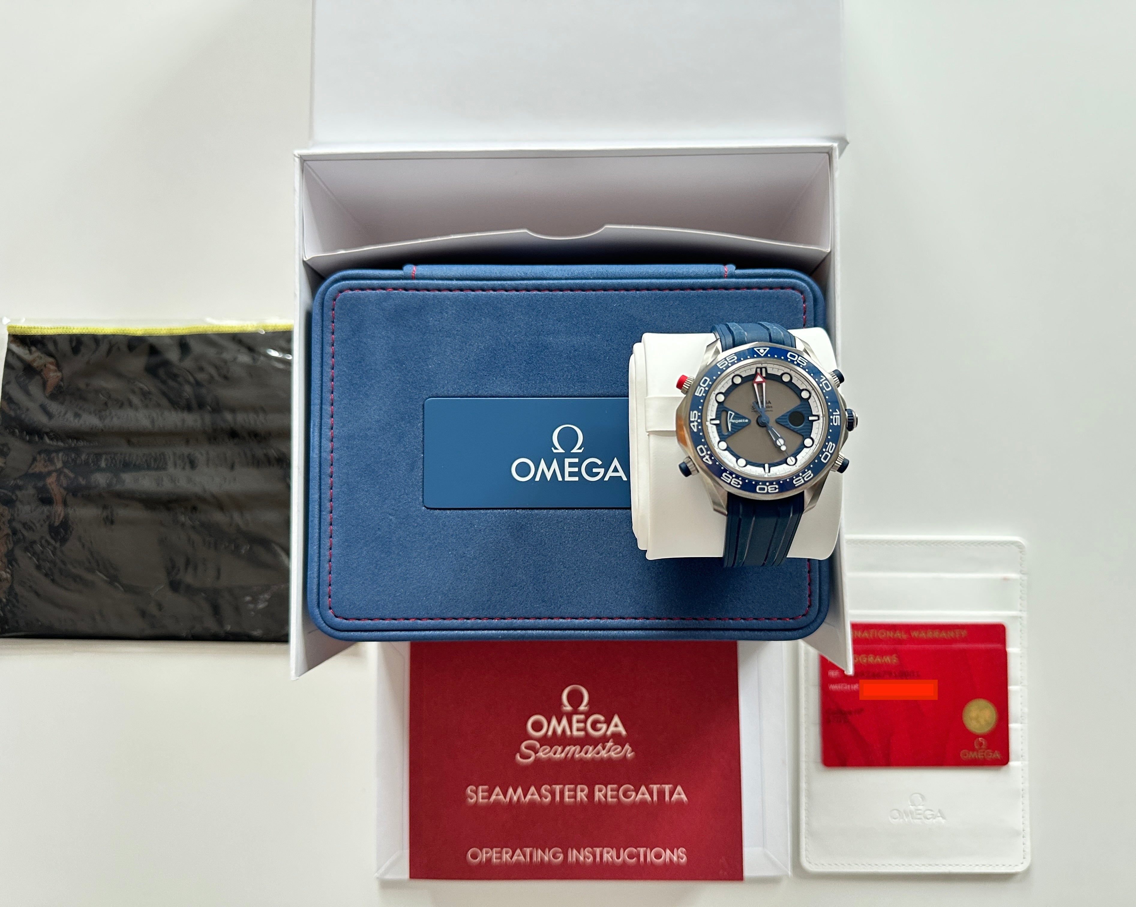 Omega Seamaster Regatta Chronograph aus Titan mit blauem Armband, im geöffneten Omega-Etui mit Garantiekarte