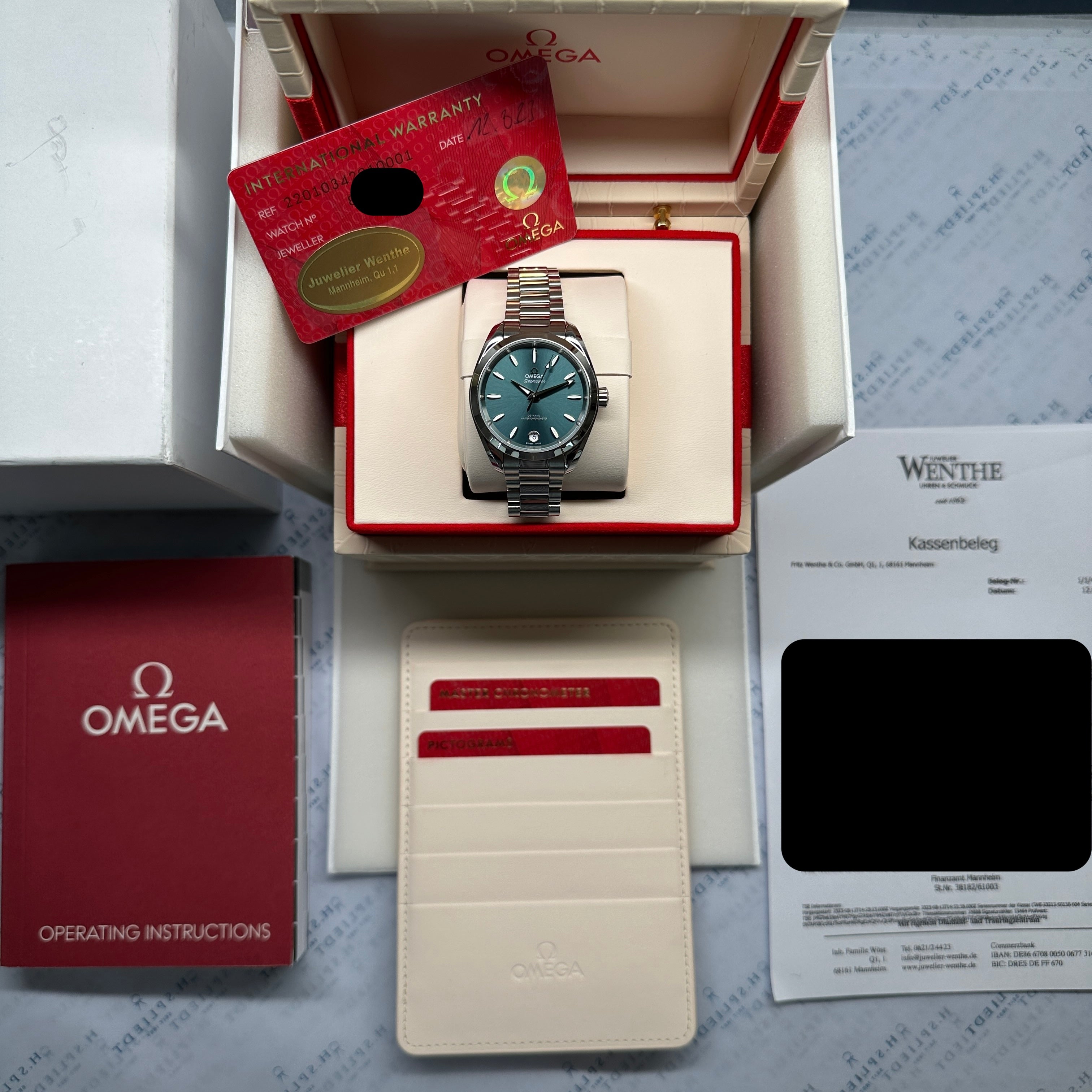 Omega Seamaster Aqua Terra 34 mm inPetrol mit Stahlarmband in geöffneter Verpackung mit Papieren