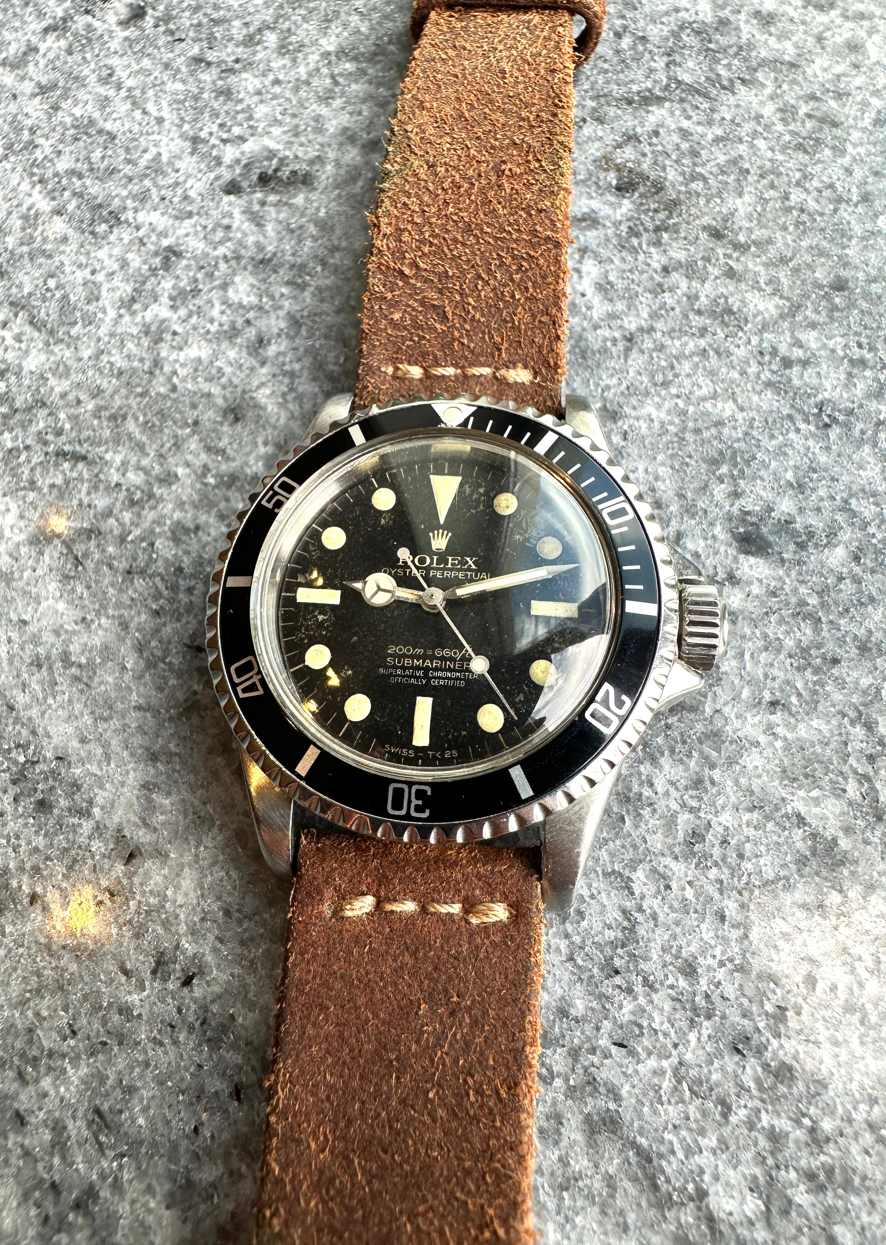 Rolex Submariner Ref 5512 von 1963 mit braunem Lederarmband auf Steinhintergrund