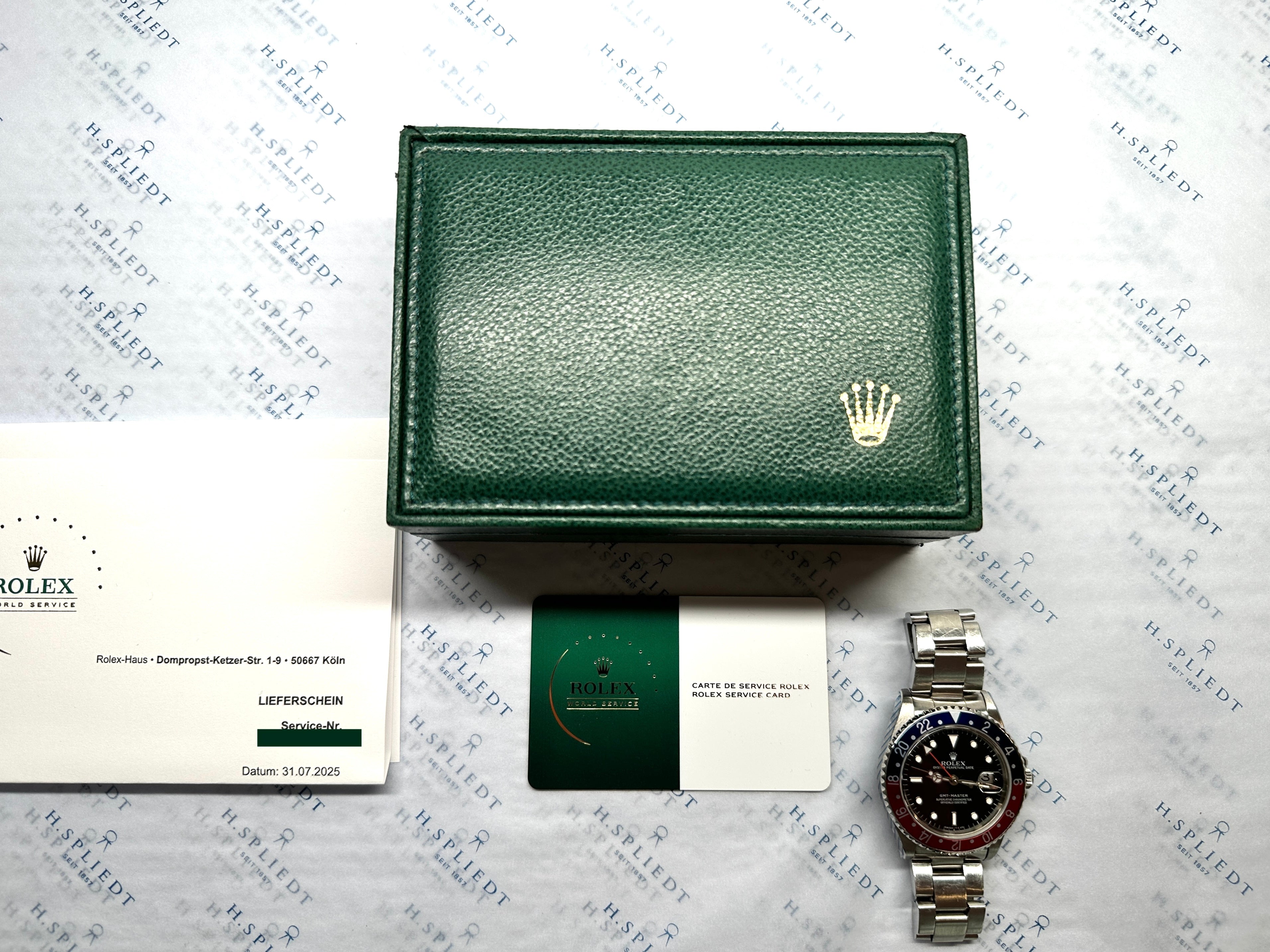 Rolex GMT-Master Pepsi 16700 mit Stahlgehäuse und Armband auf geprägtem Hintergrund mit Garantiekarte und Box