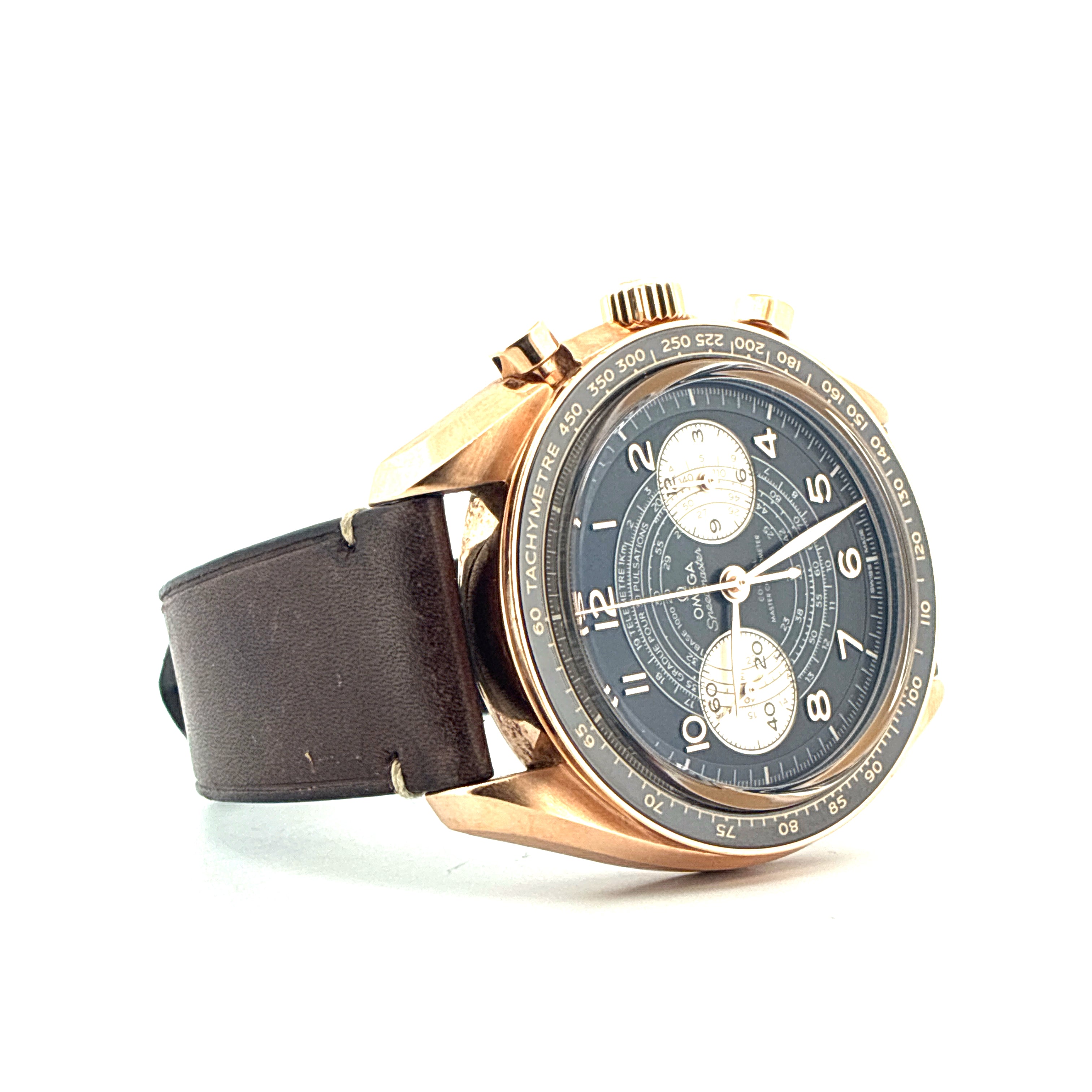 Omega Speedmaster Chronoscope aus Gelbgold mit dunkelblauem Zifferblatt und braunem Lederarmband auf weißem Hintergrund