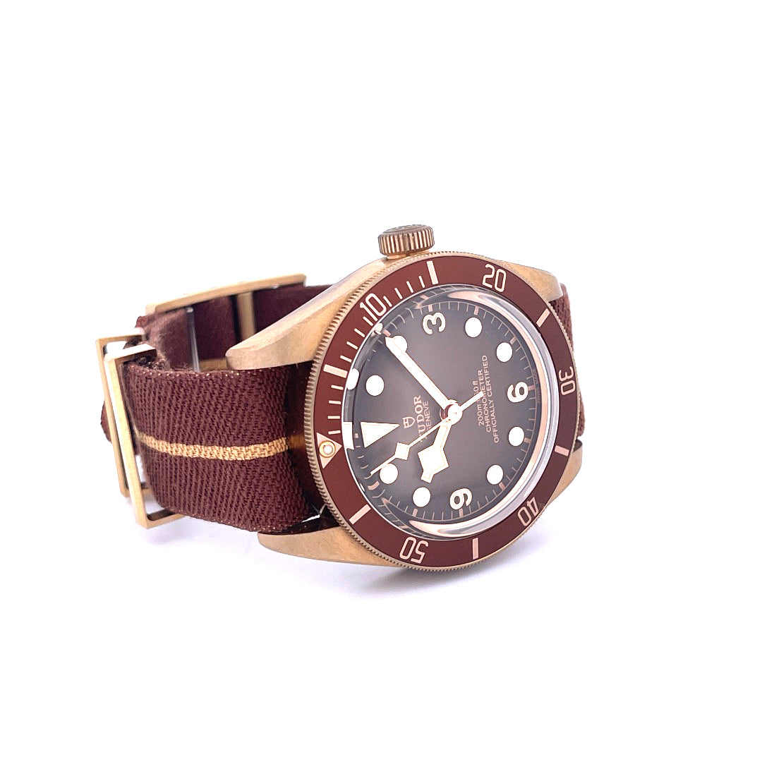 Eine Tudor Black Bay Fifty-eight Boutique Edition Uhr aus Bronze mit braunem Textilband auf weißem Hintergrund