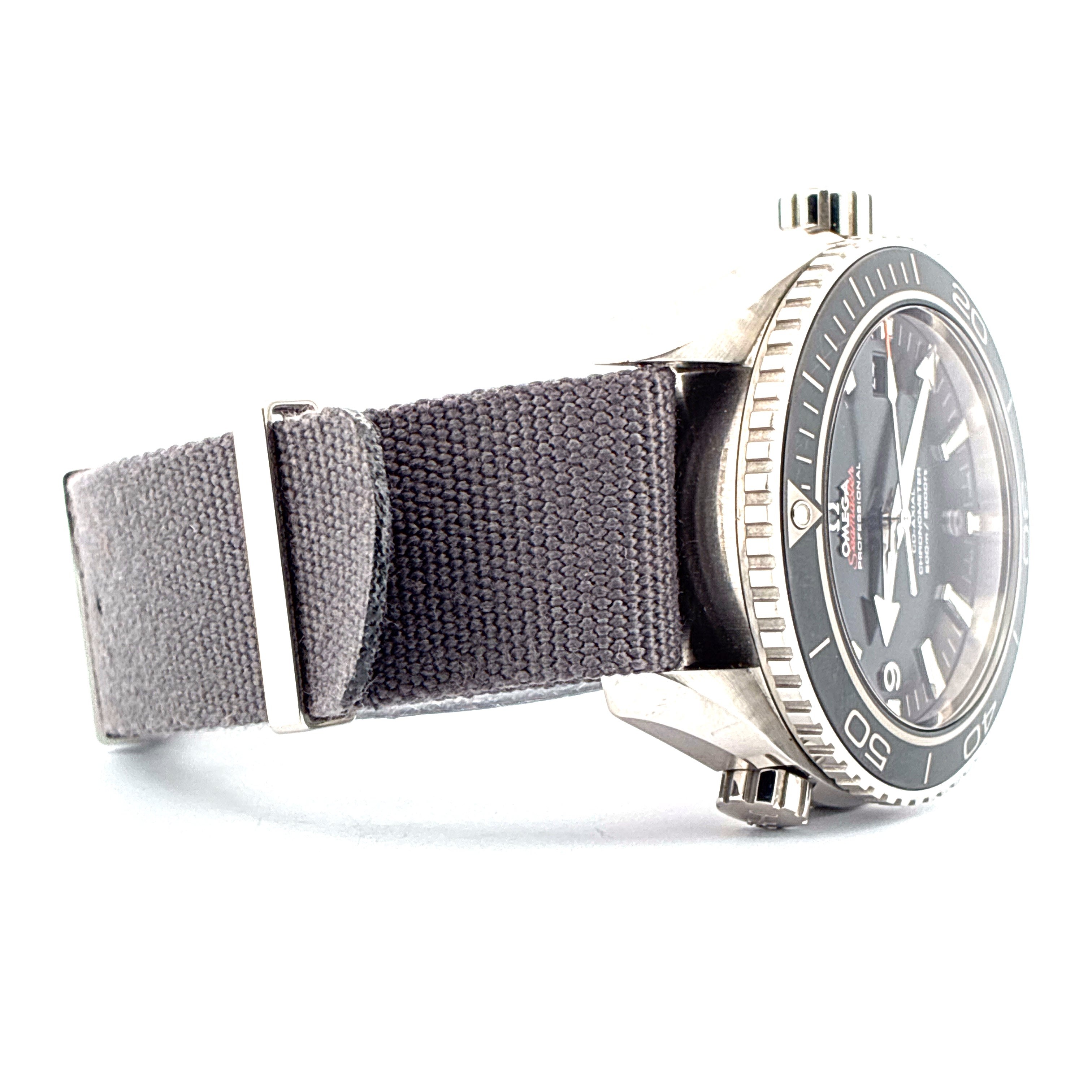 Omega Seamaster Planet Ocean mit graublauem Stoffarmband und silberner Schliesse vor weissem Hintergrund
