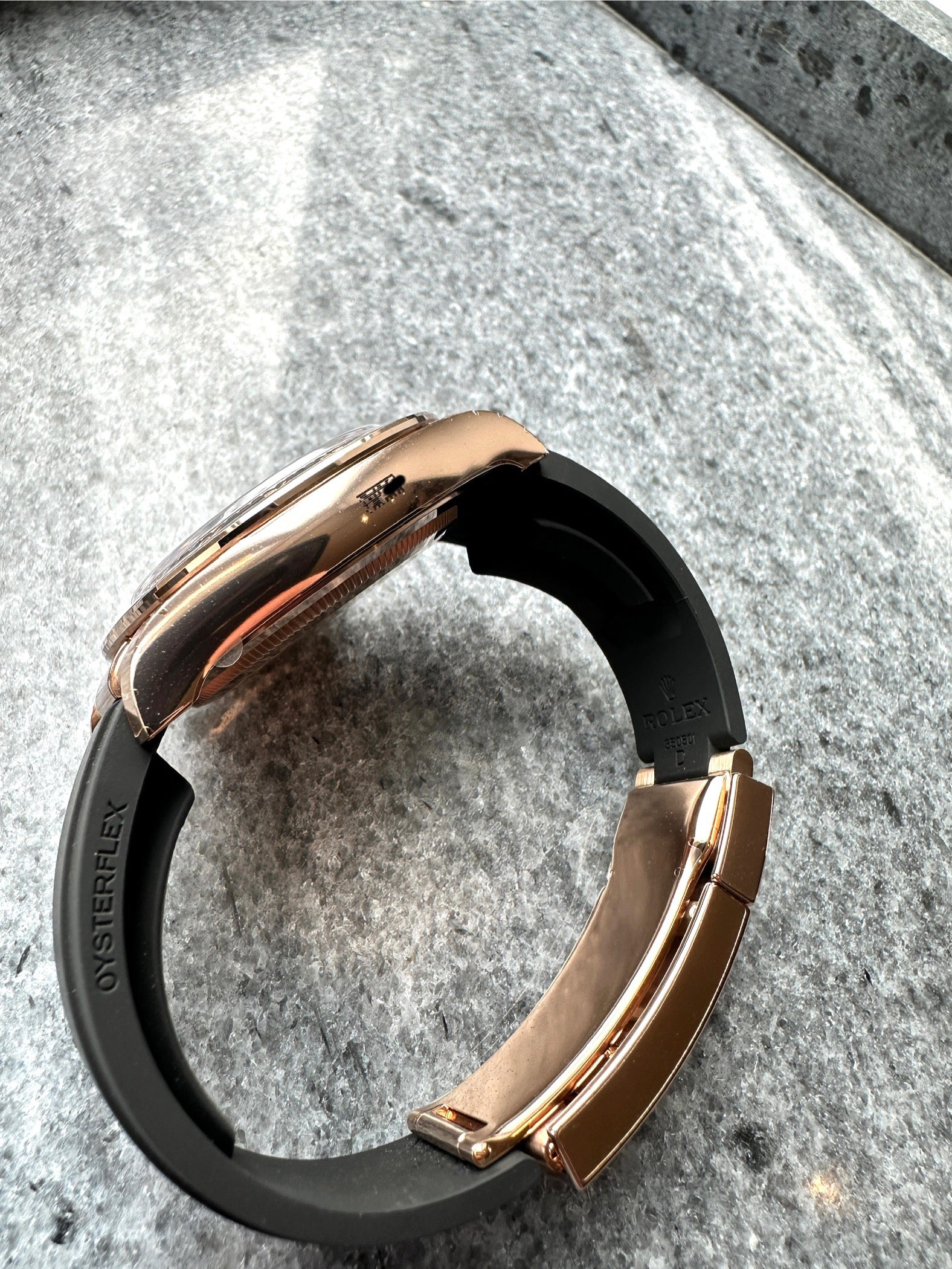 Seitenansicht einer Rolex Cosmograph Daytona aus Roségold mit schwarzem Oysterflex-Armband und Schließe