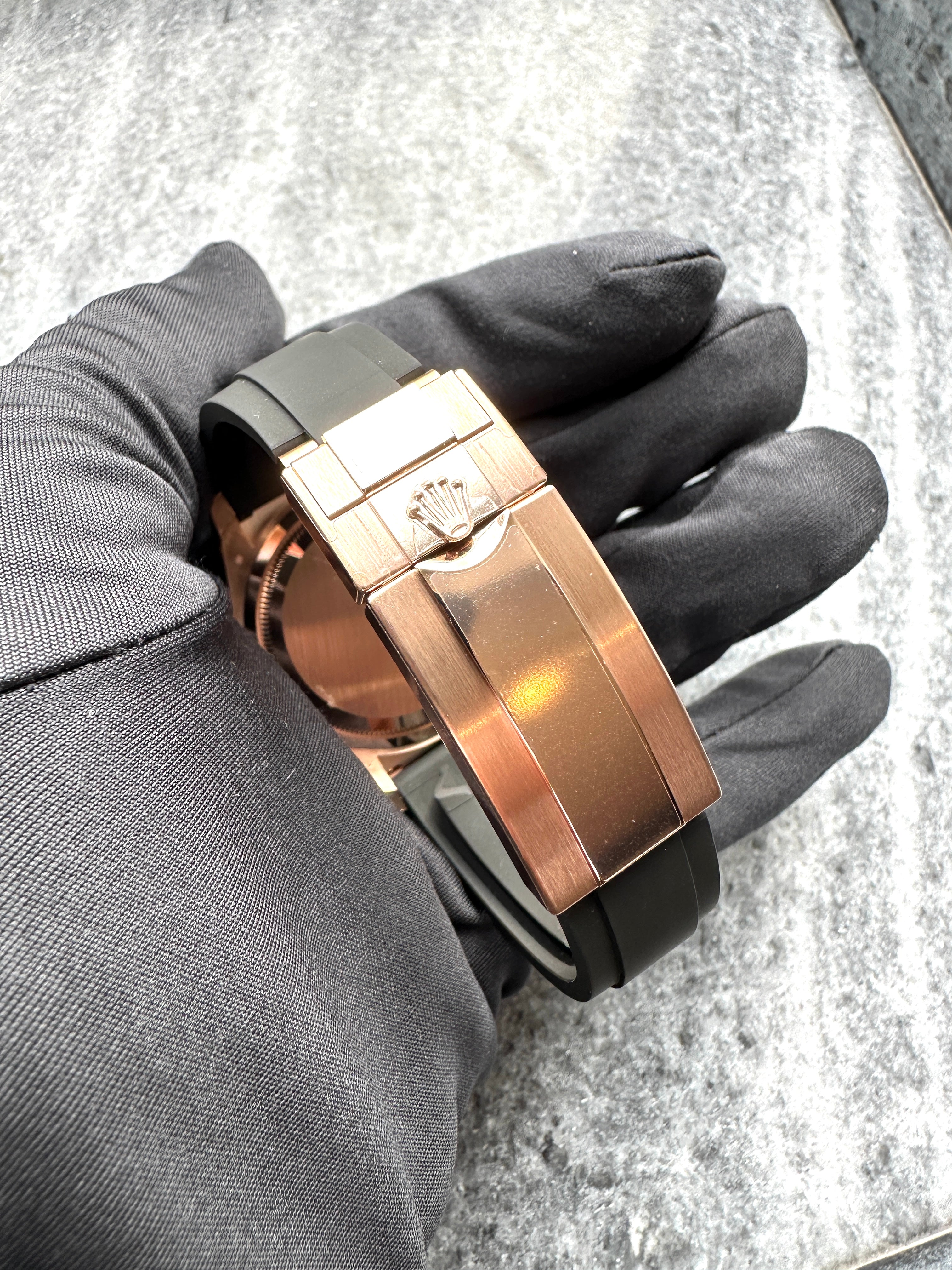 Nahaufnahme des Roségold-Faltschlosses einer Rolex Cosmograph Daytona Chocolate 126515LN mit schwarzem Kautschukarmband