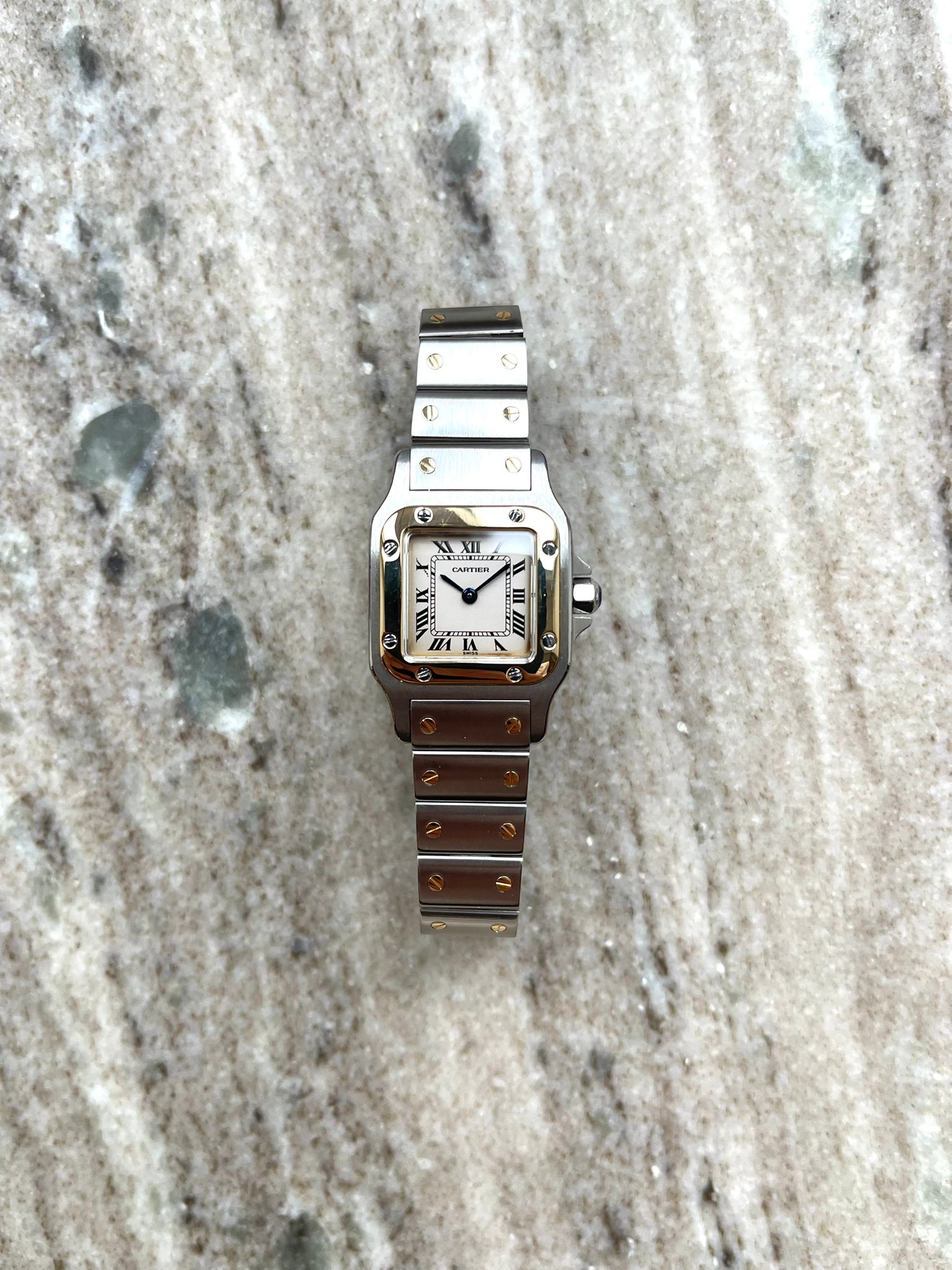 Cartier Santos Galbée Damenuhr mit Stahl- und Gelbgoldgehäuse und Armband auf Marmor