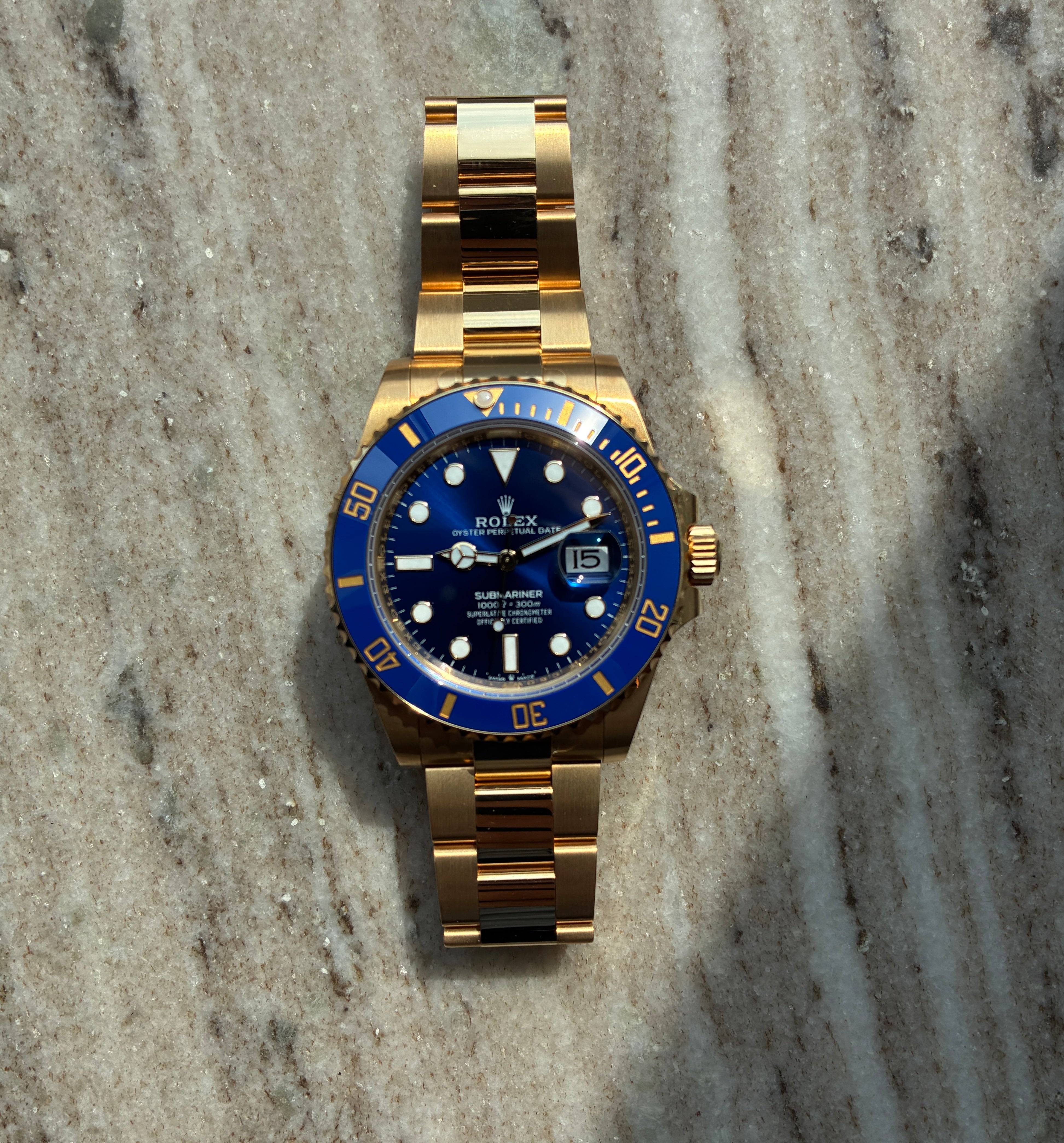 Rolex Submariner Date 41 mm Gelbgold mit blauem Zifferblatt auf marmoriertem Hintergrund