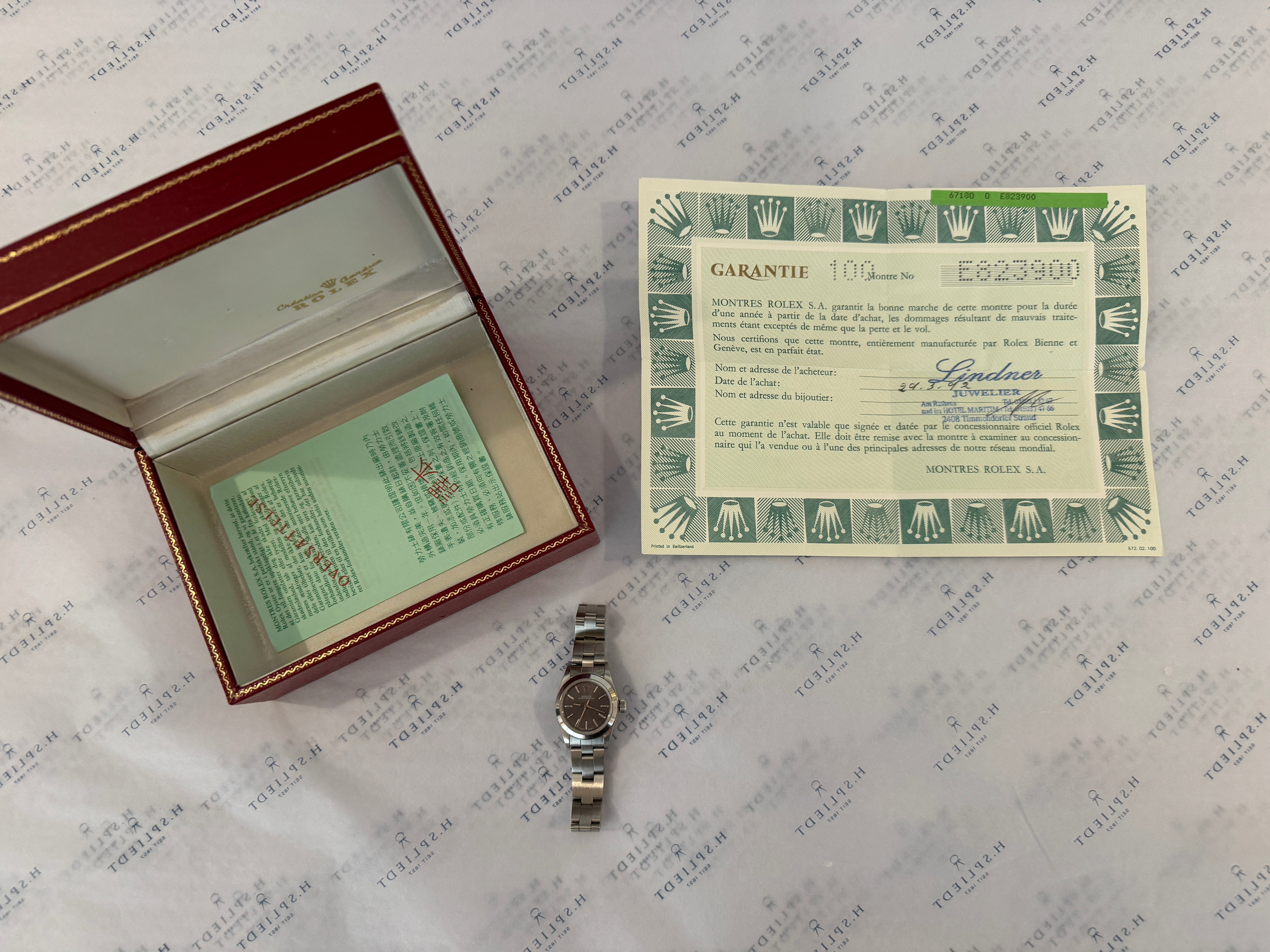 Rolex Oyster Perpetual Lady gebraucht im Karton mit Garantiekarte auf gemustertem Papier