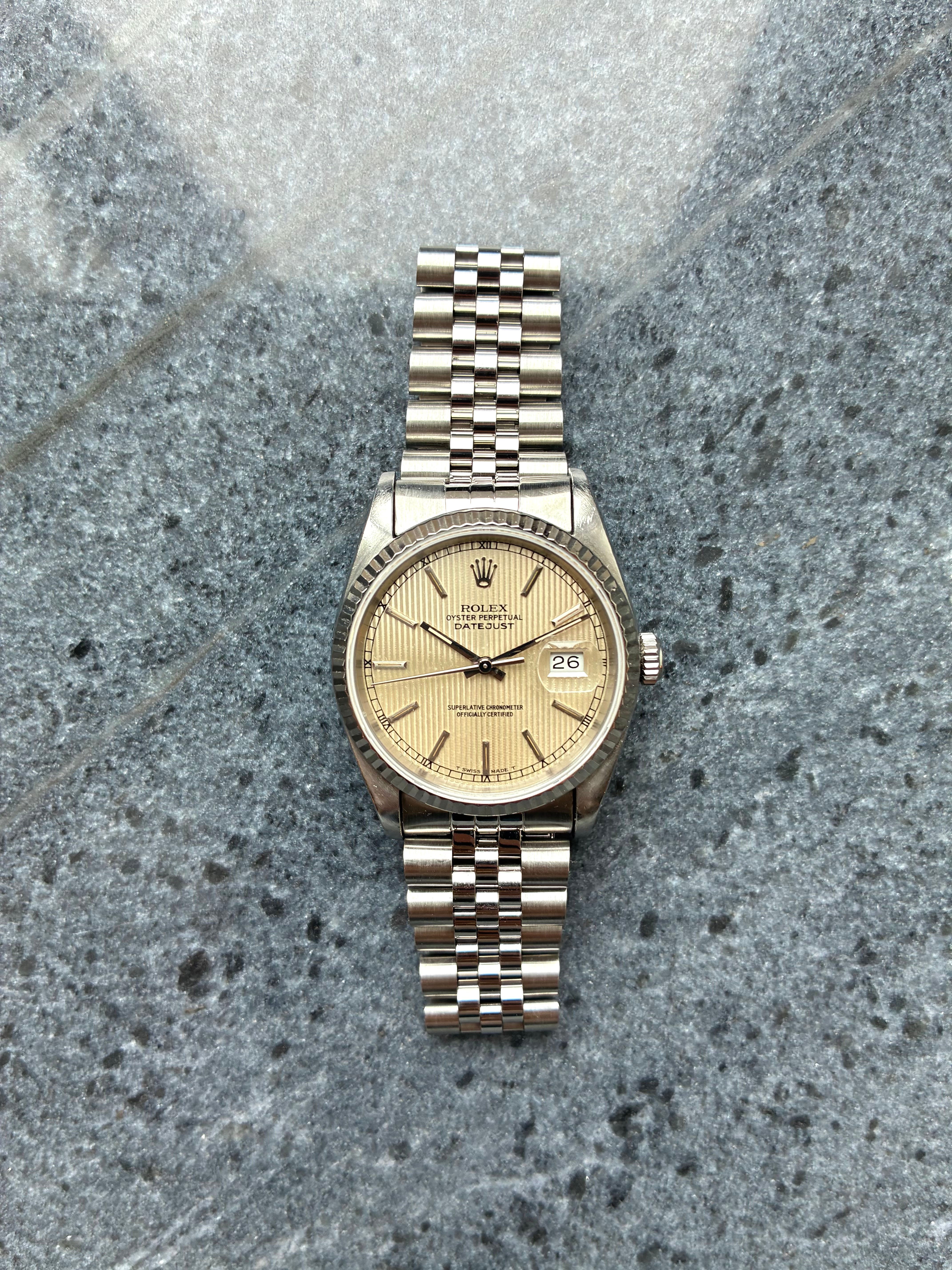 Eine Rolex Datejust 36 mm aus Stahl mit silbrigem Zifferblatt und Datum, auf grauem Steinuntergrund