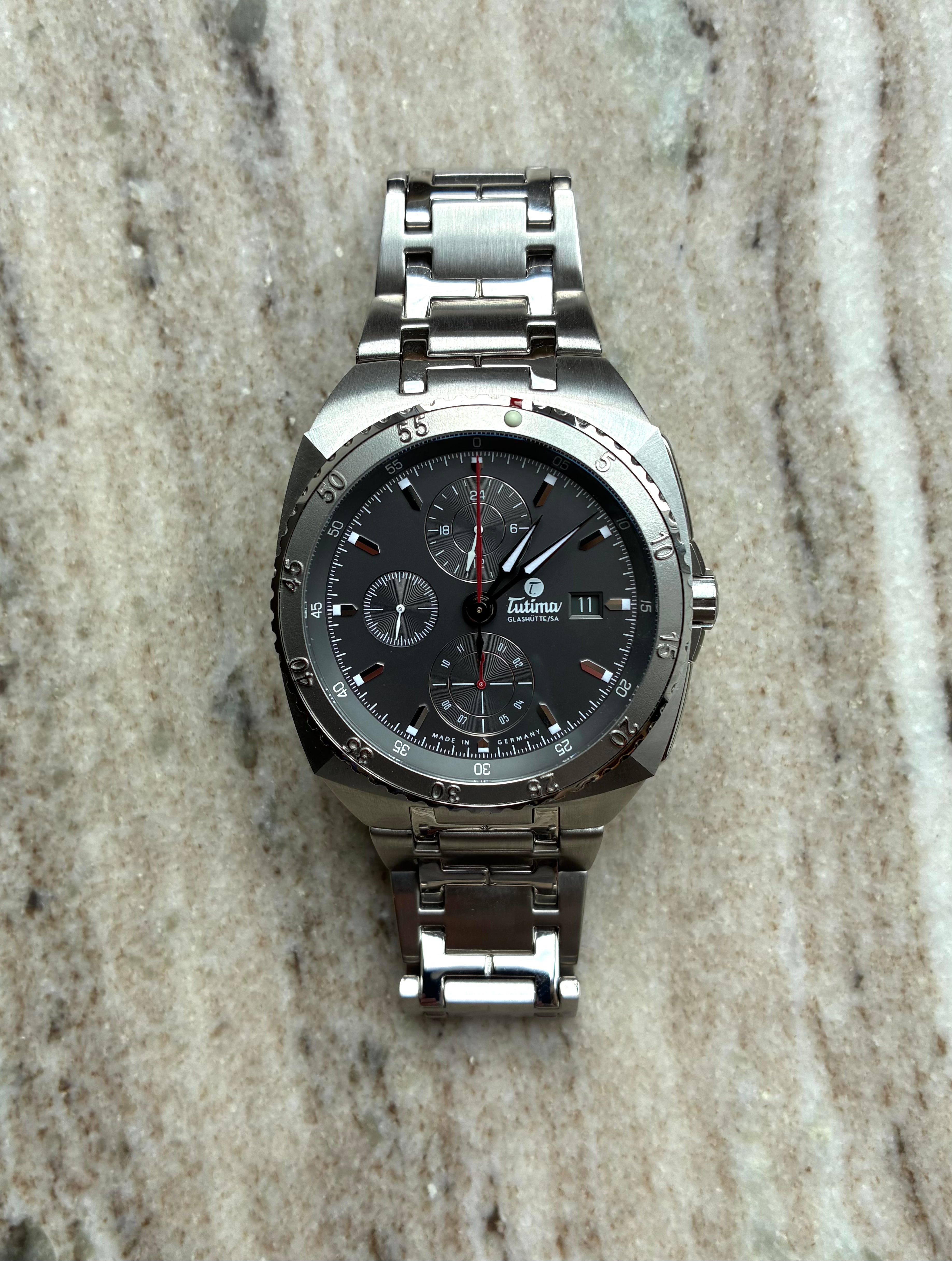 Tutima Saxon One Chronograph mit Stahlgehäuse und grauem Zifferblatt auf Marmorhintergrund