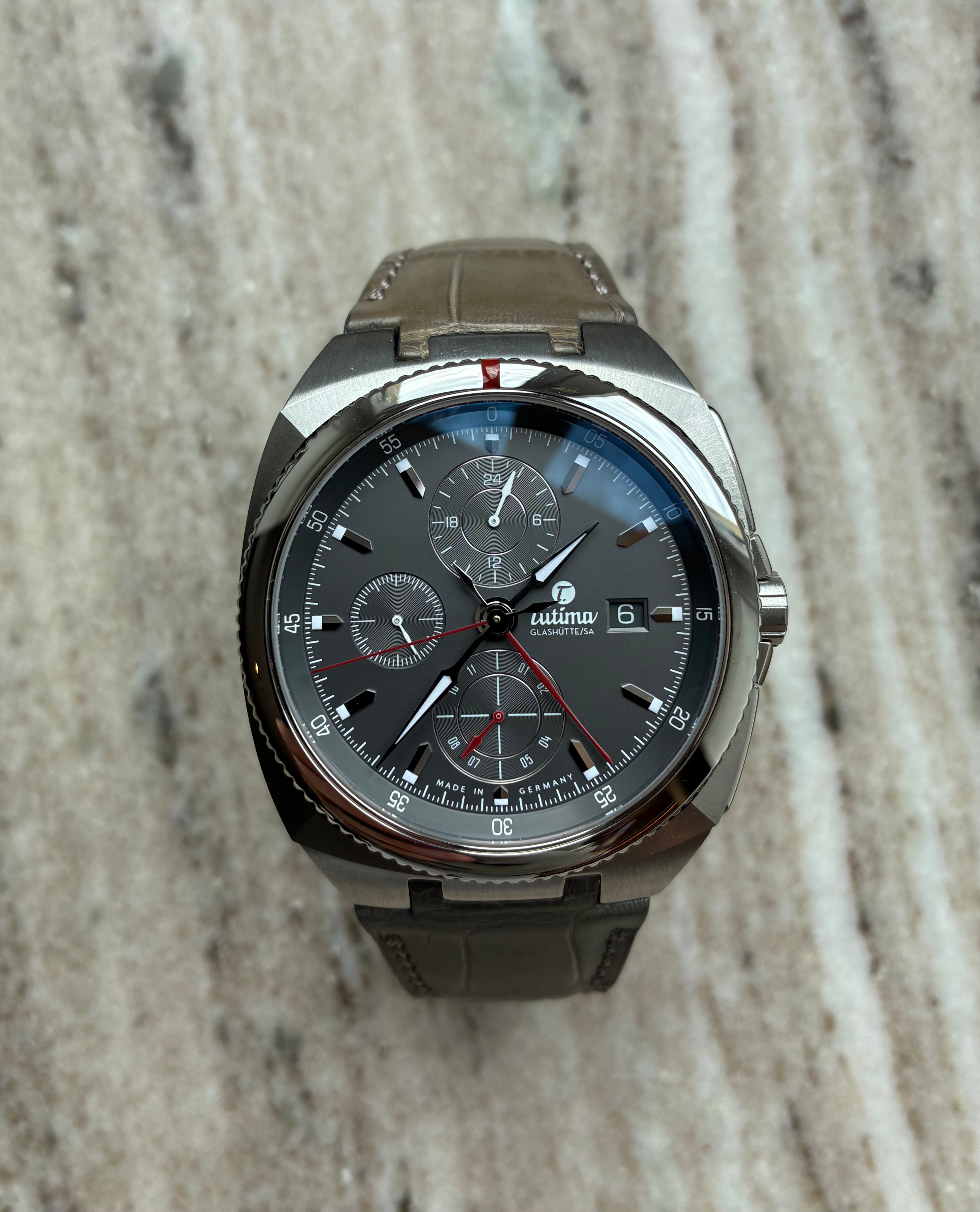 Tutima Saxon One Chronograph mit grauem Zifferblatt und grauem Lederarmband auf Marmor Hintergrund