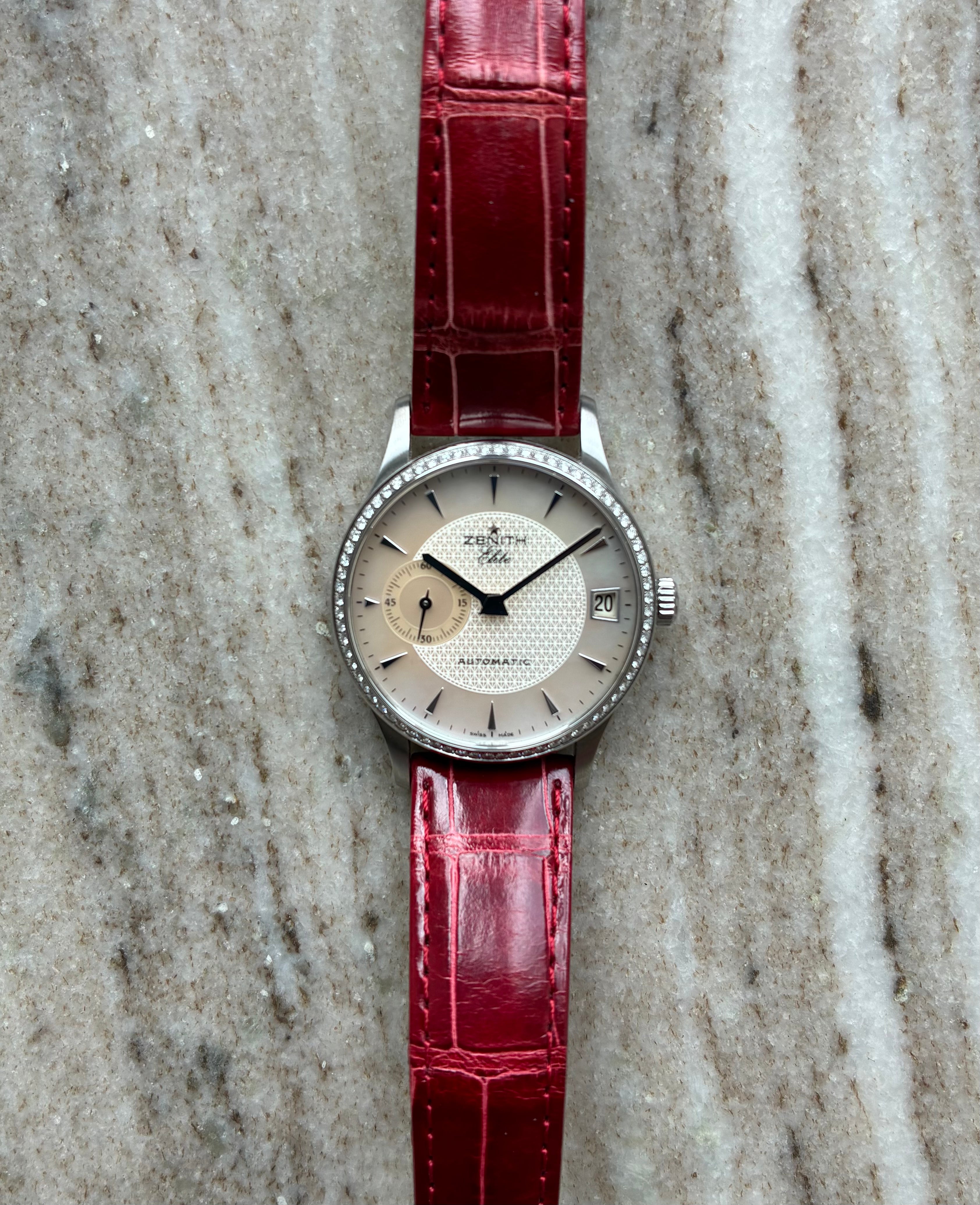 Zenith Class Elite Automatic Ladies Watch 33mm mit Diamantlünette und rotem Lederarmband auf Marmoruntergrund