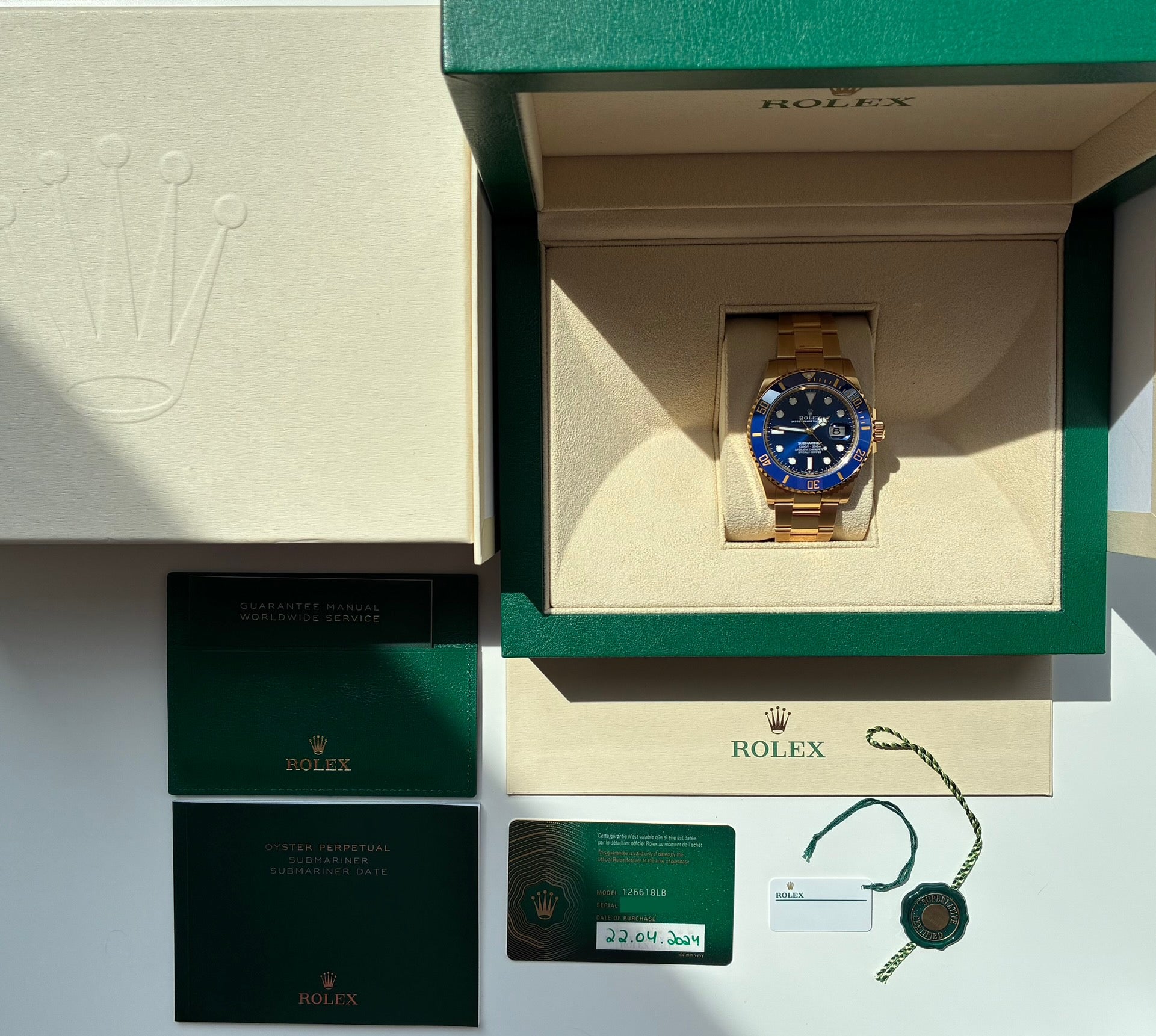 Rolex Submariner Date in Gelbgold, im geöffneten Karton liegend, mit Papieren und Hangtag