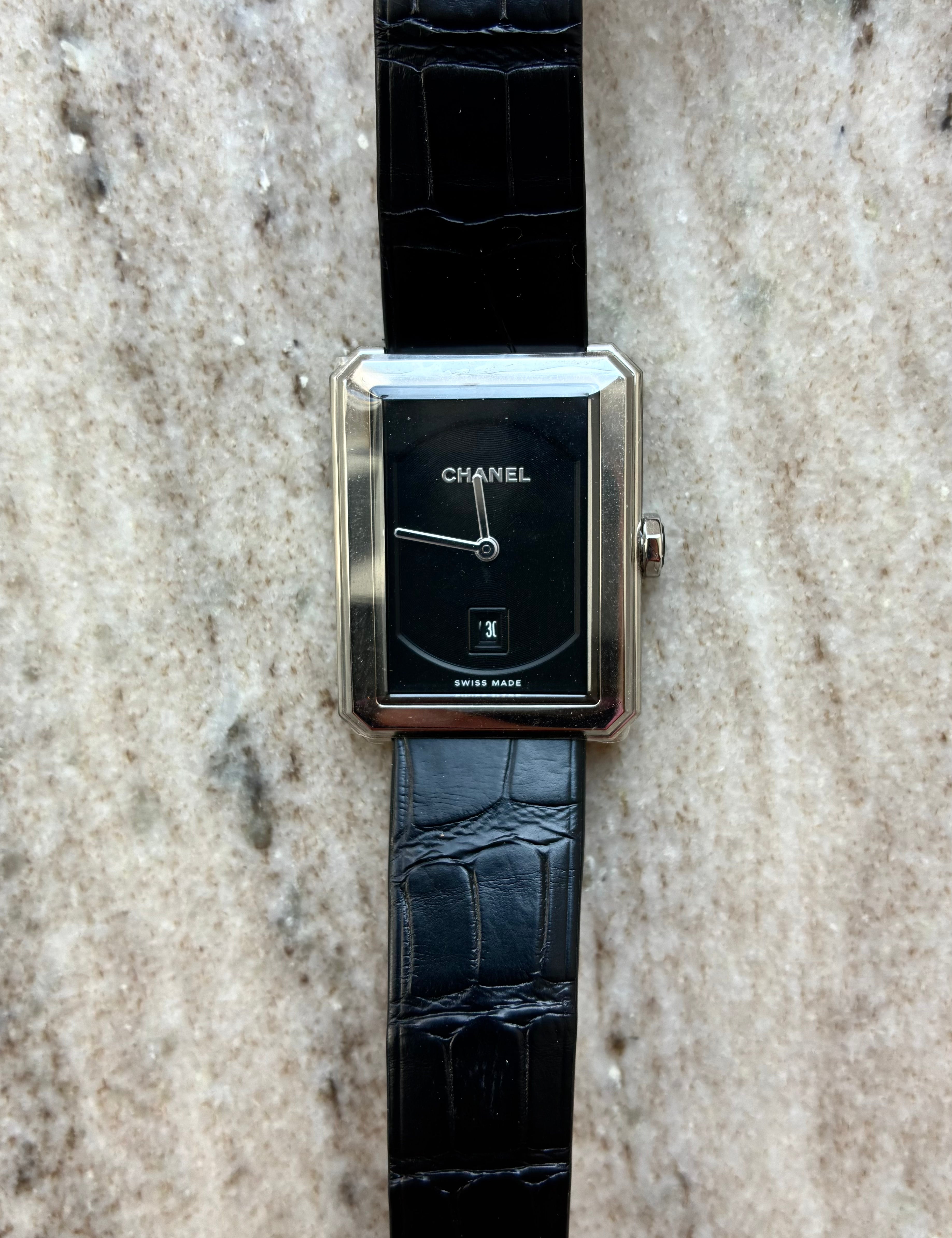 Chanel Boyfriend Uhr mit schwarzem Zifferblatt und Lederarmband auf Steinboden