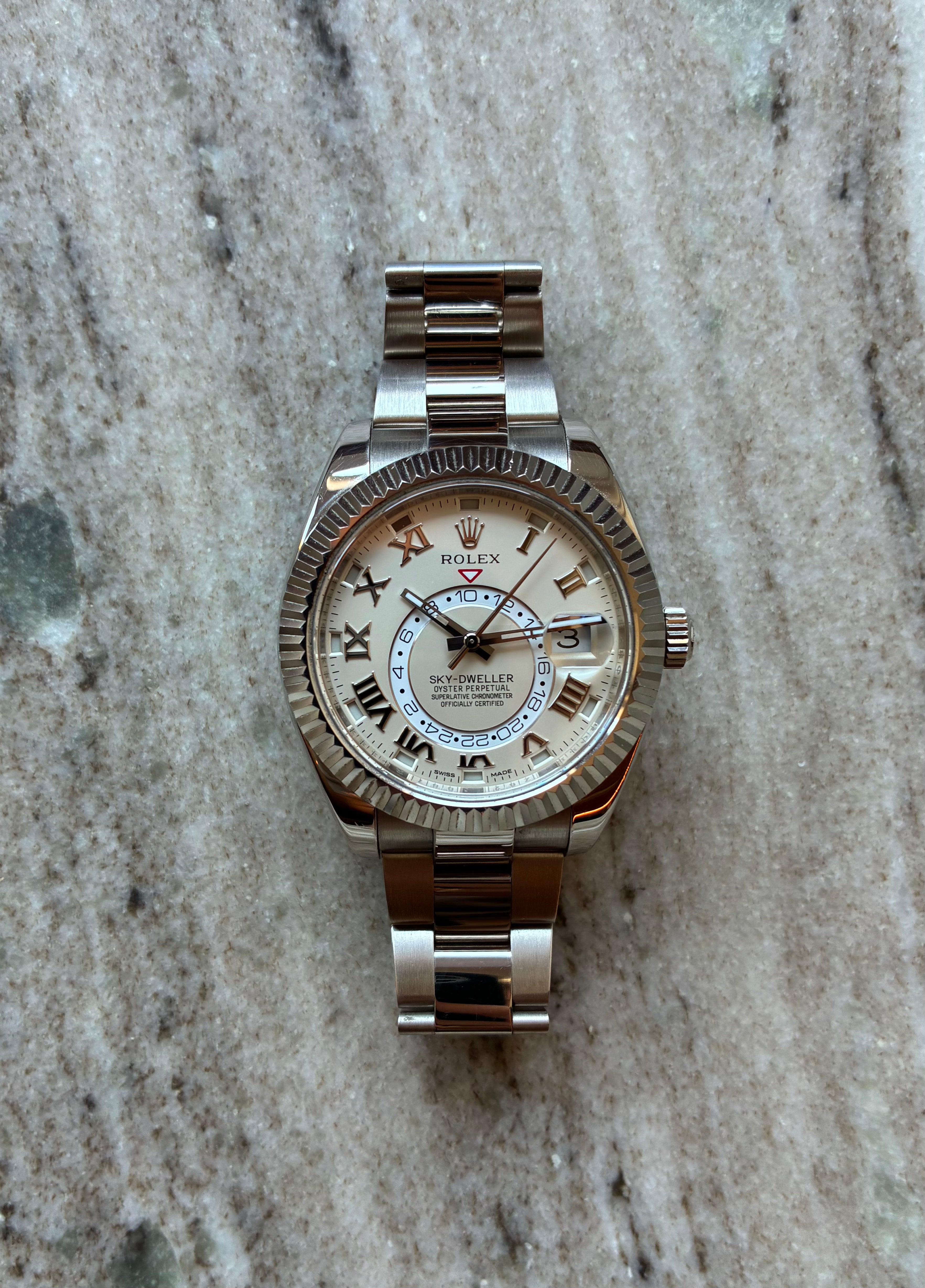 Rolex Sky Dweller 42mm Weißgold Automatik mit weißem Zifferblatt auf Marmoruntergrund