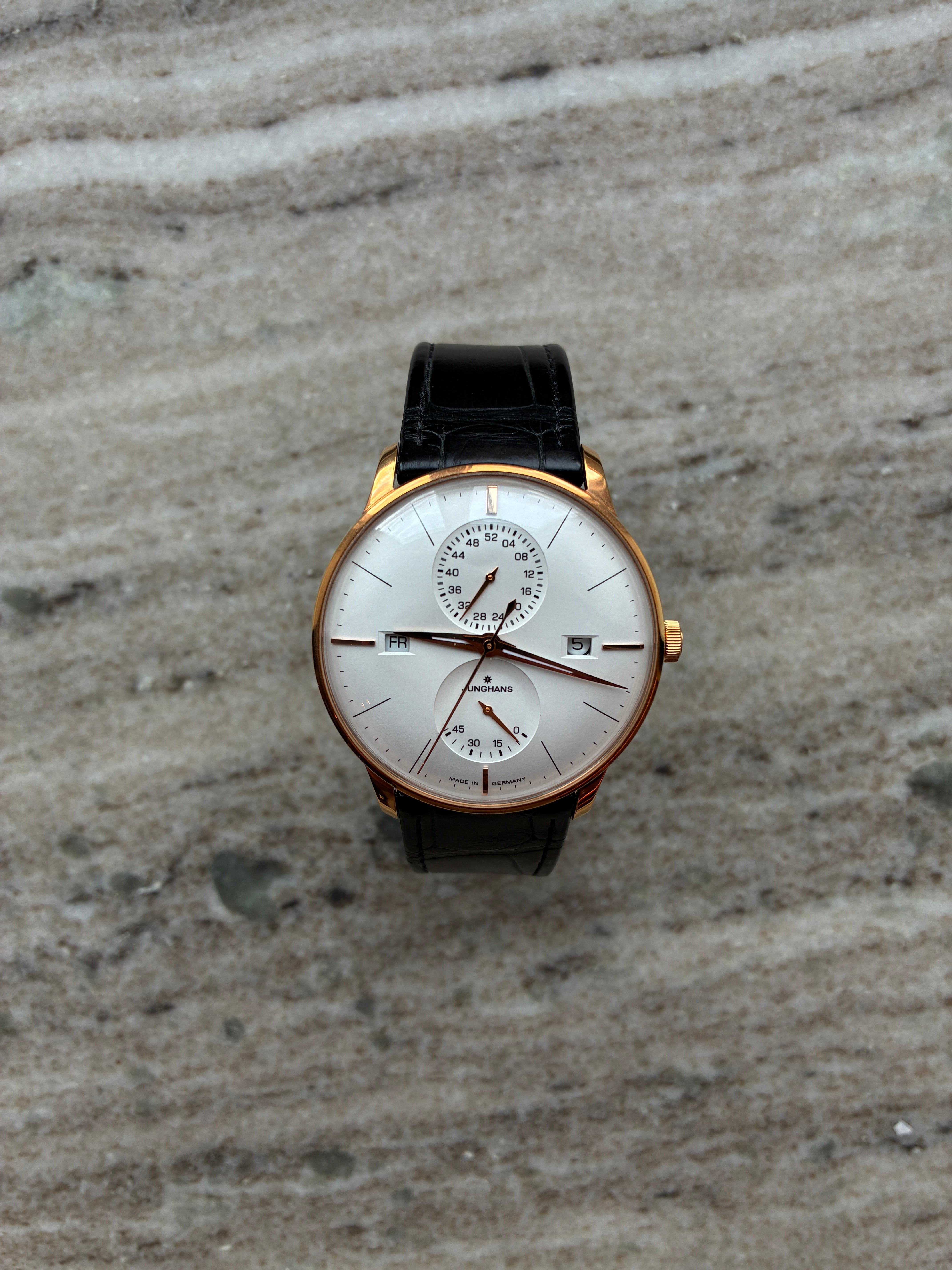Junghans Meister Agenda rosévergoldete Uhr mit schwarzem Lederarmband und silbernem Zifferblatt auf Marmoruntergrund