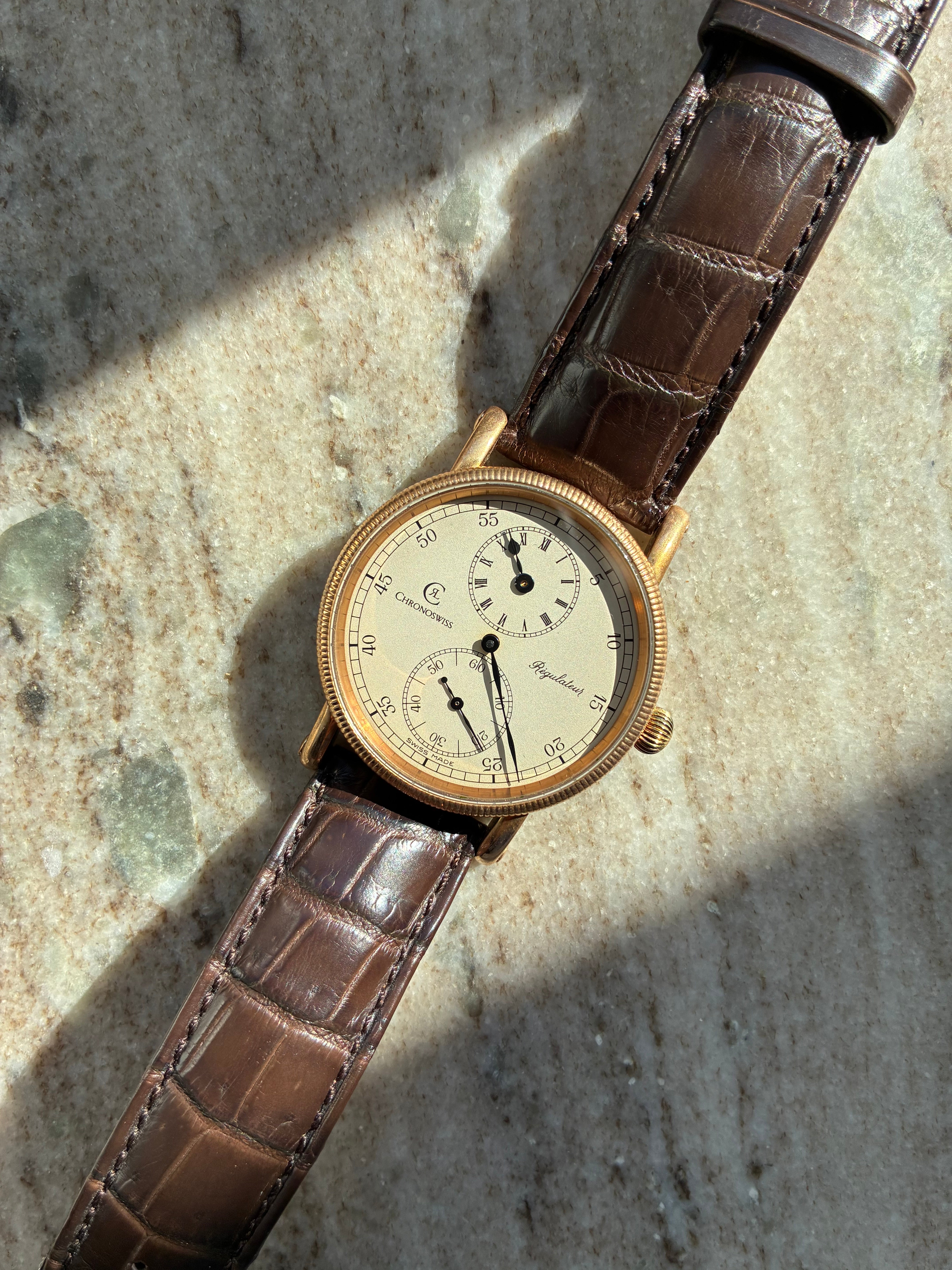 Chronoswiss Regulateur Bronze 2025 von oben auf Marmor mit braunem Kroko-Armband