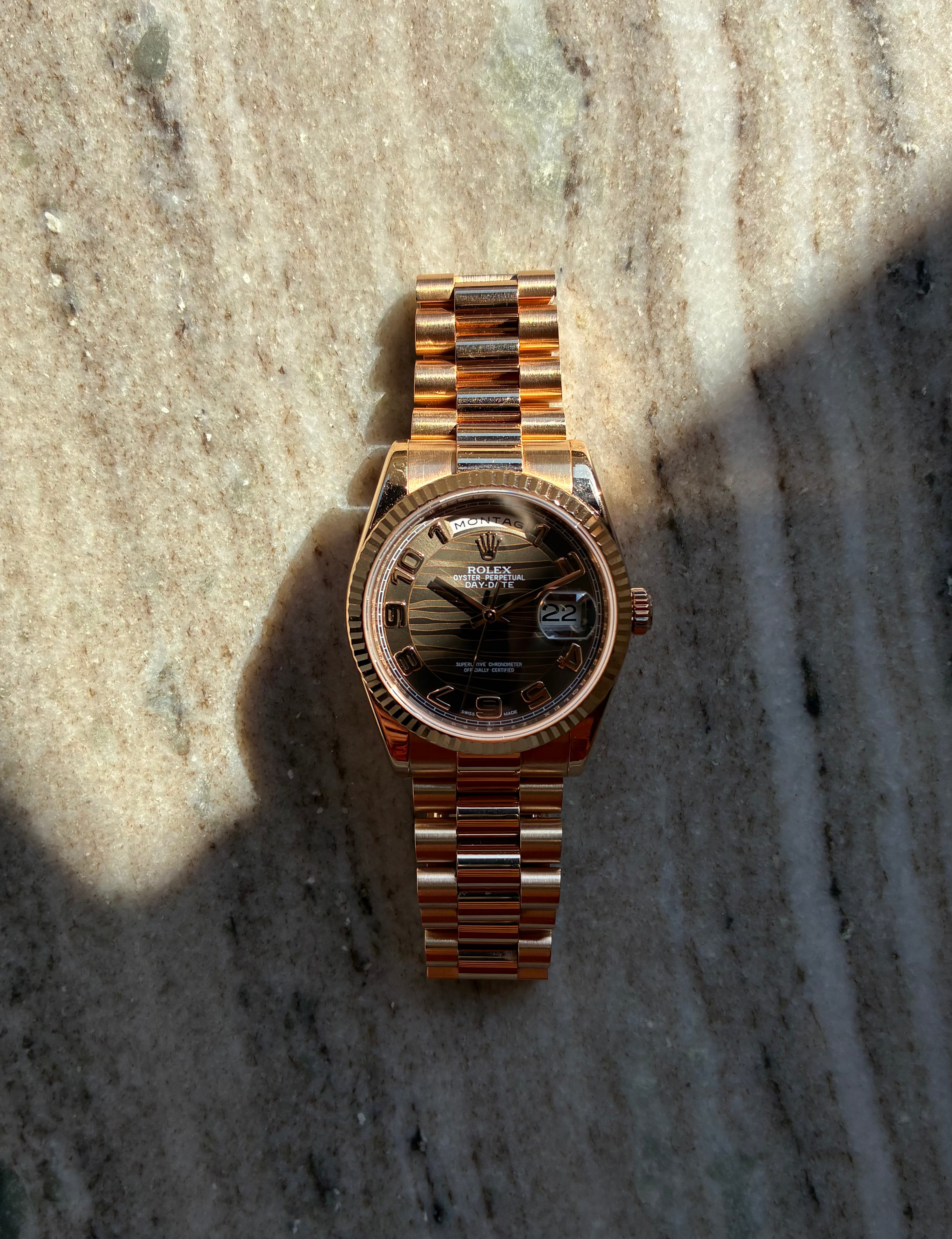 Rolex Day-Date 36 Everose mit Wave Dial auf Marmoruntergrund mit Sonnenlicht