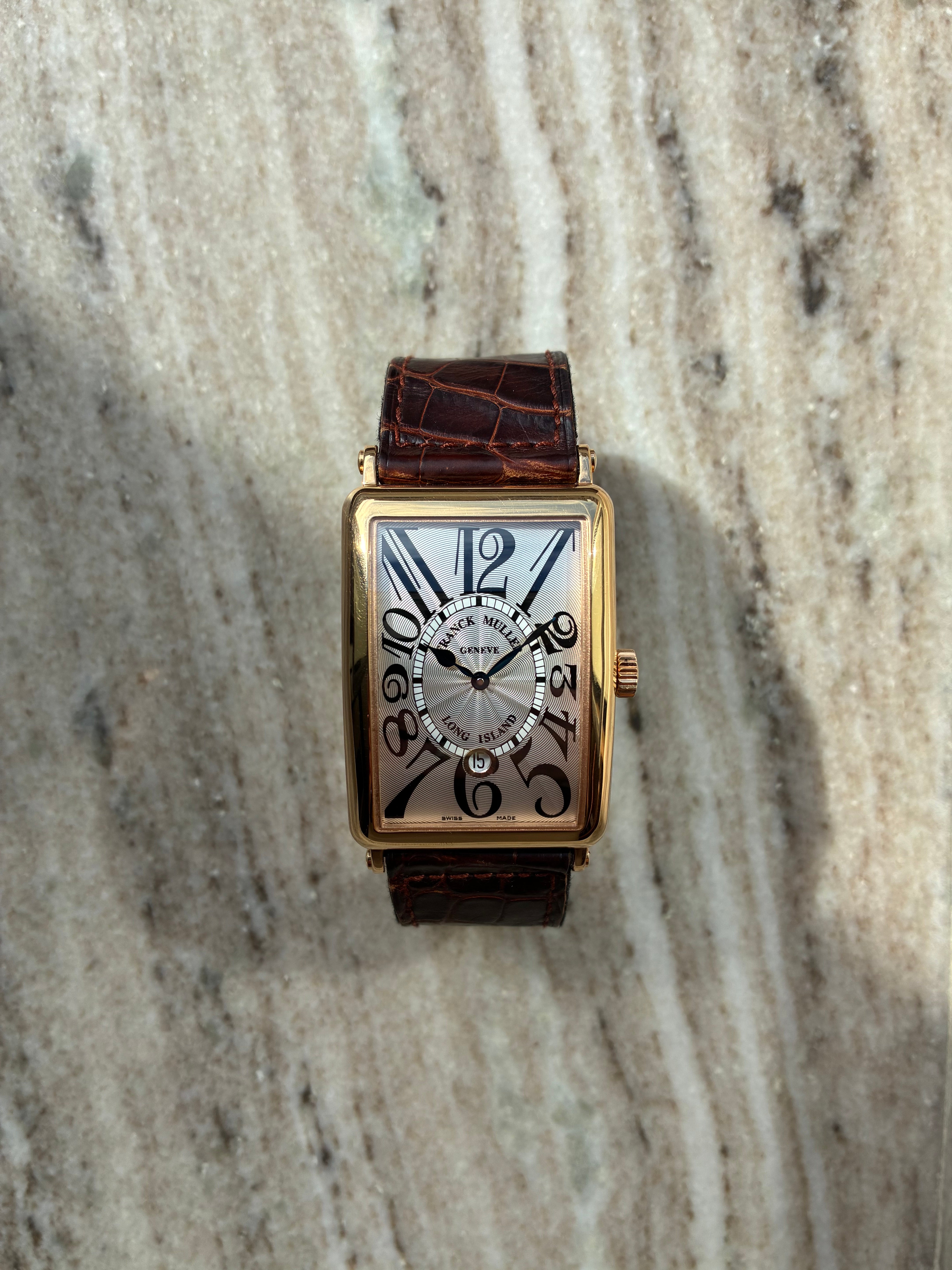 Franck Muller Long Island Roségold auf Marmoruntergrund, Frontansicht, mit silbernem Zifferblatt und braunem Krokodillederarmband