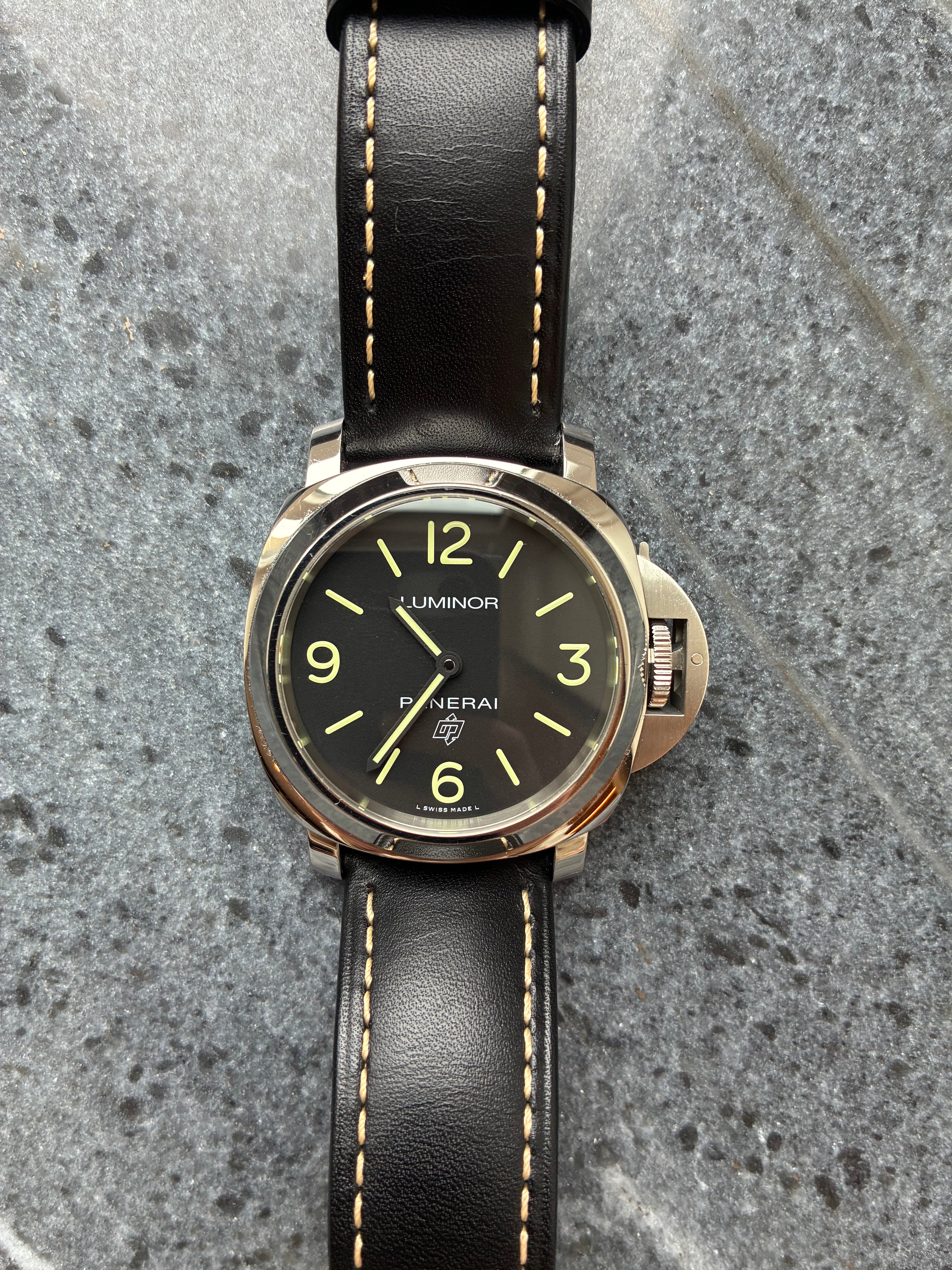 Panerai Luminor Base Logo (2018) Uhr mit schwarzem Zifferblatt und schwarzem Lederarmband auf Steinhintergrund