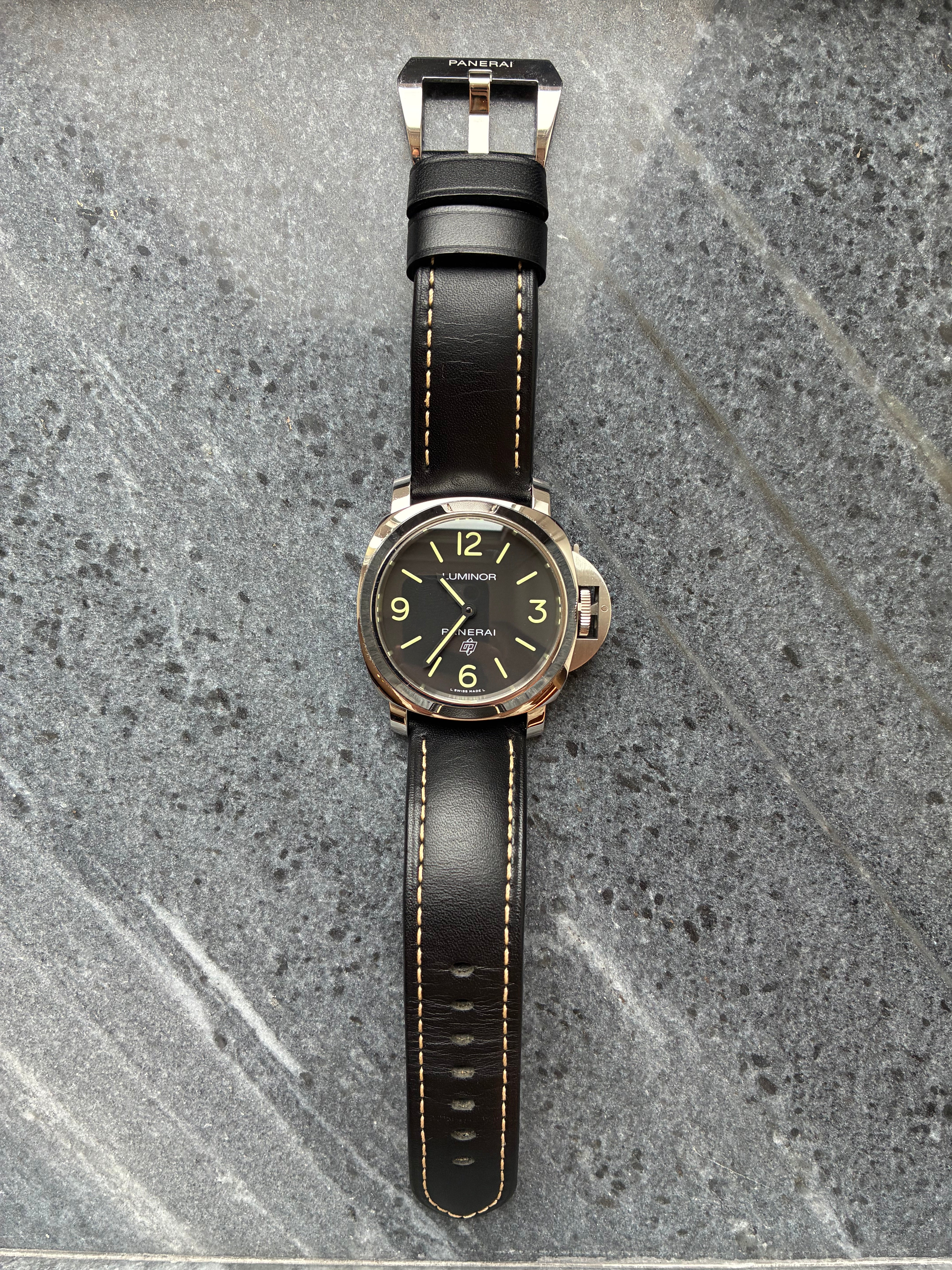 Panerai Luminor Base Logo von 2018 mit schwarzem Lederarmband und hellem Zifferblatt auf grauem Untergrund