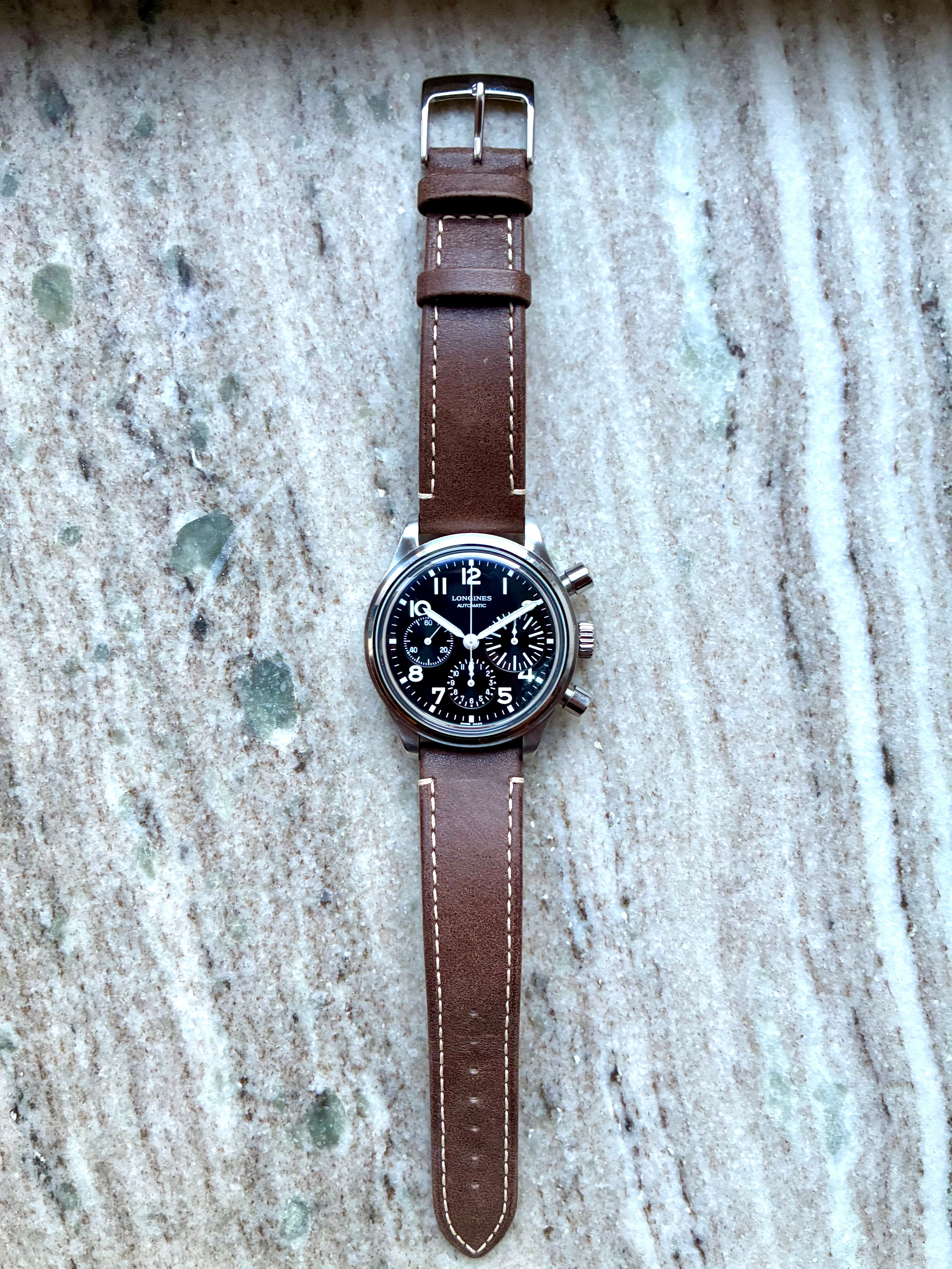 Longines Avigation Bigeye Automatik Uhr mit braunem Lederarmband auf Marmorhintergrund