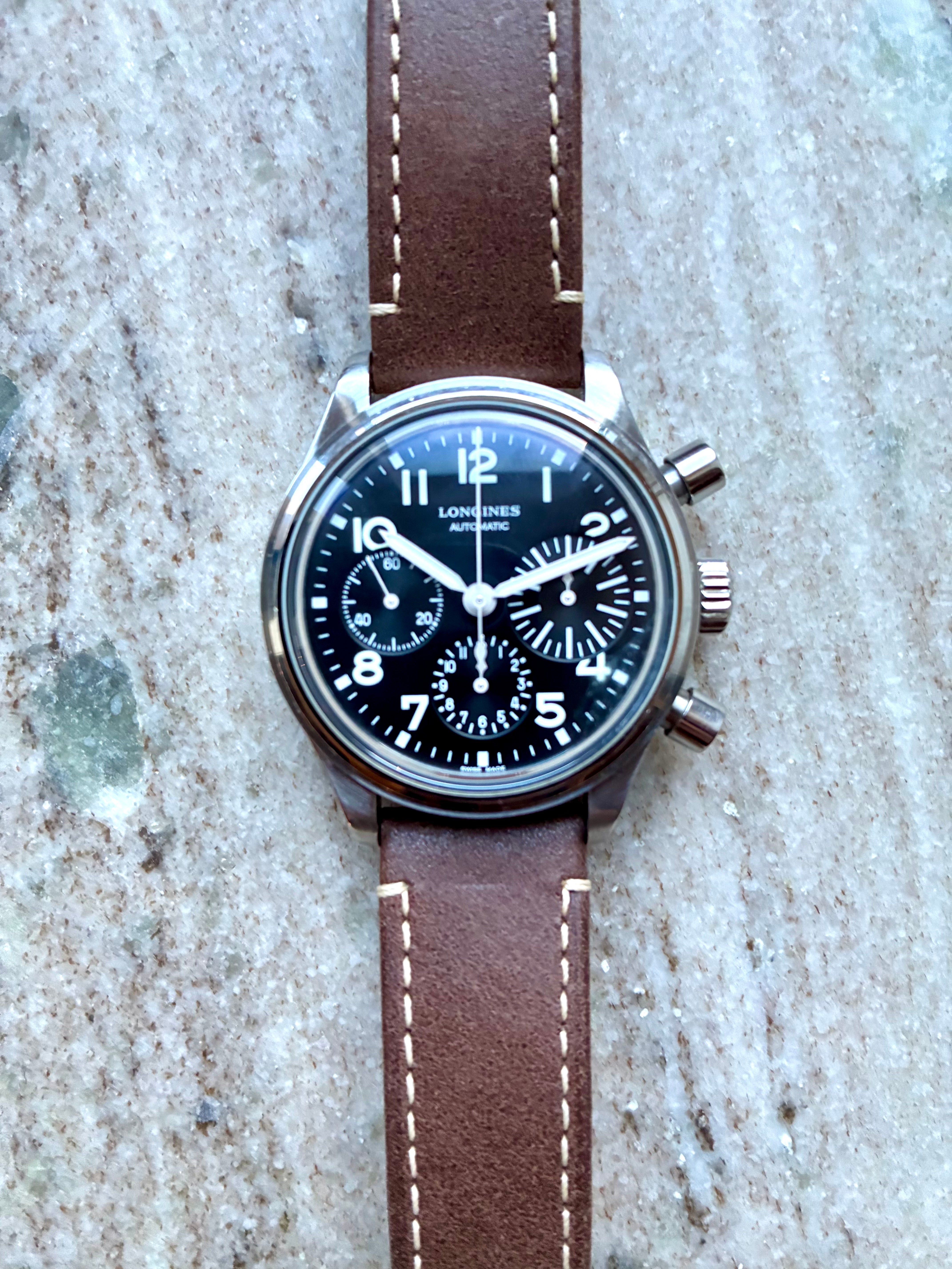 Longines Avigation Bigeye Herrenuhr mit braunem Lederarmband und schwarzem Zifferblatt auf Steinhintergrund
