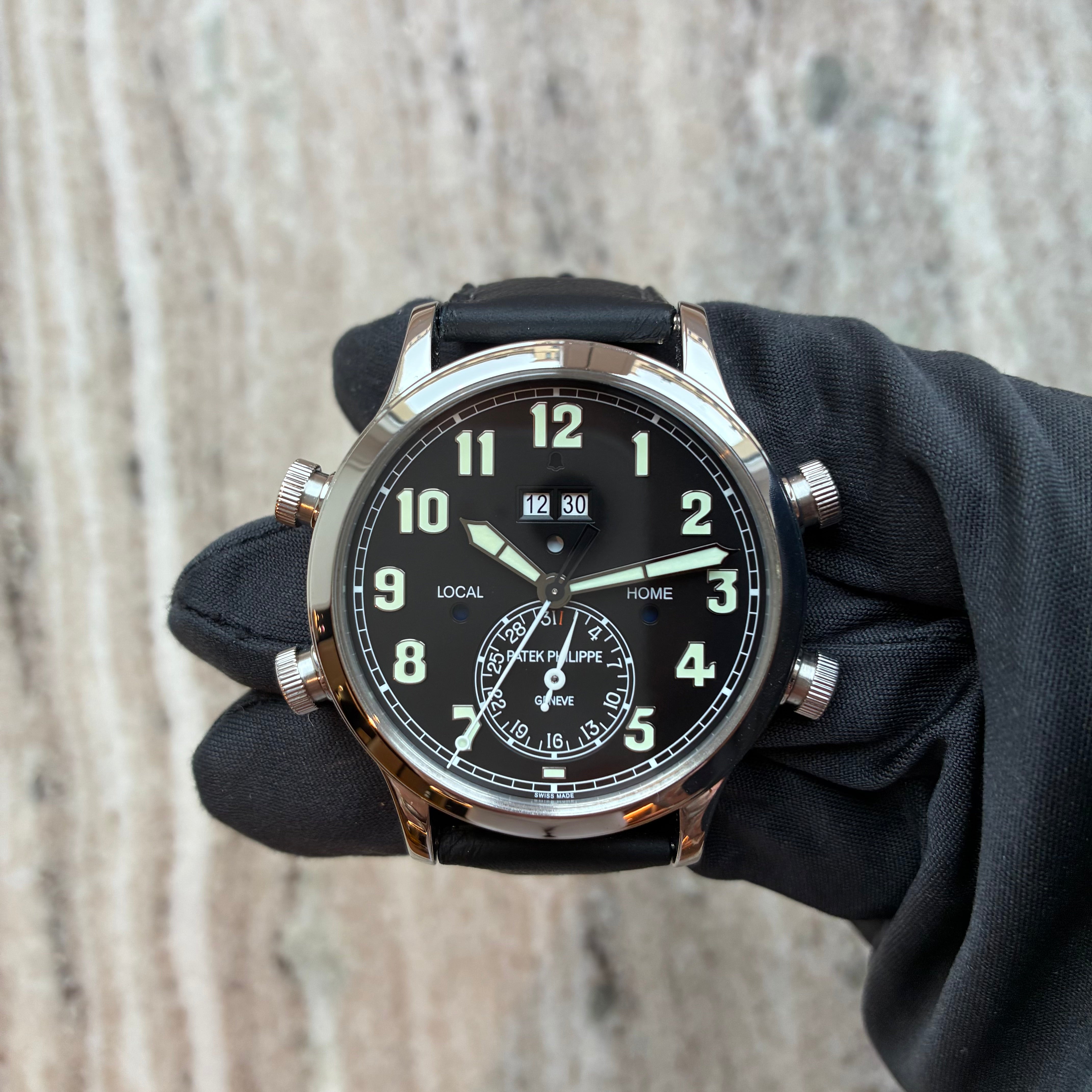 Patek Philippe Grandes Complications Alarm Travel Uhr mit schwarzem Zifferblatt und weissen Indizes auf Marmorhintergrund