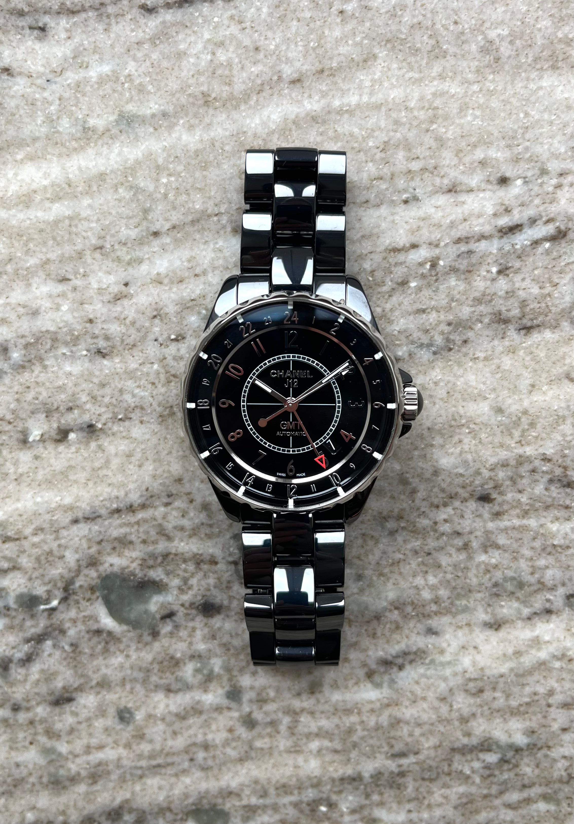 Chanel J12 GMT Keramik schwarz mit 24-Stunden-Anzeige auf marmoriertem Hintergrund