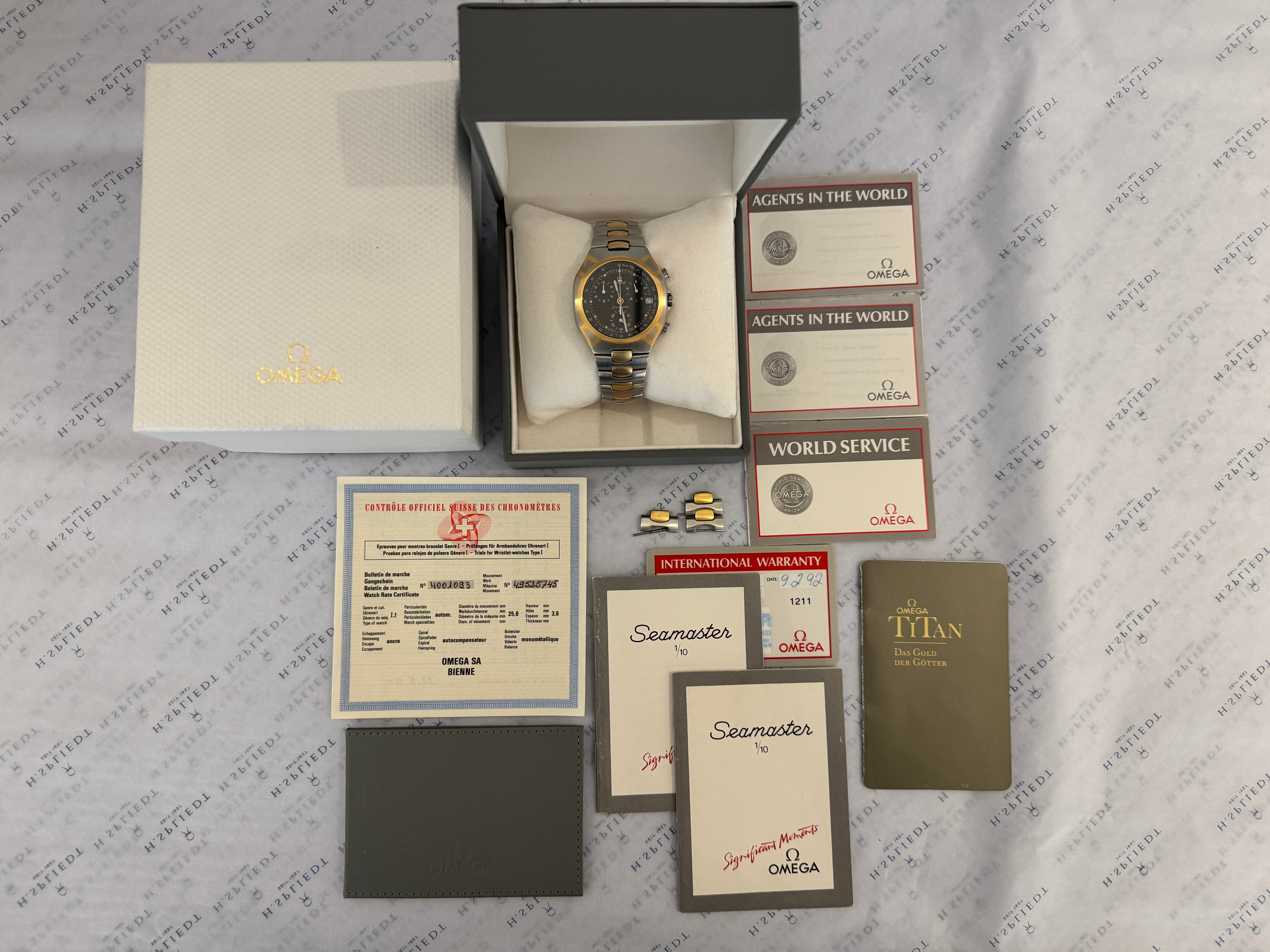 Omega Seamaster Polaris Chronograph mit Gold-Stahl-Gehäuse und Zubehör auf gemustertem Hintergrund