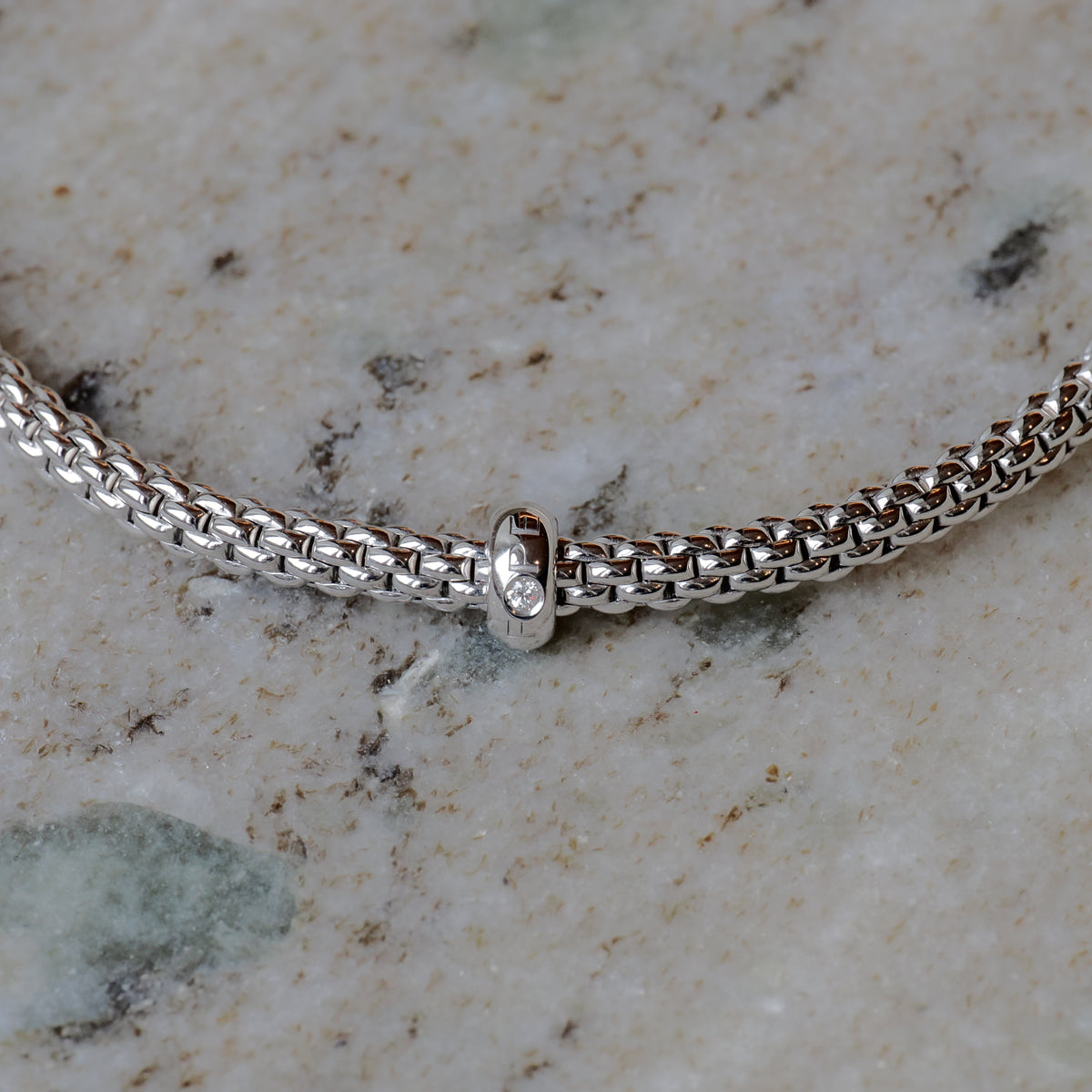 Fope Prima Flex it Armband in Weißgold mit Diamant Größe M, Detailansicht mit Kette und Fassung vor neutralem Hintergrund