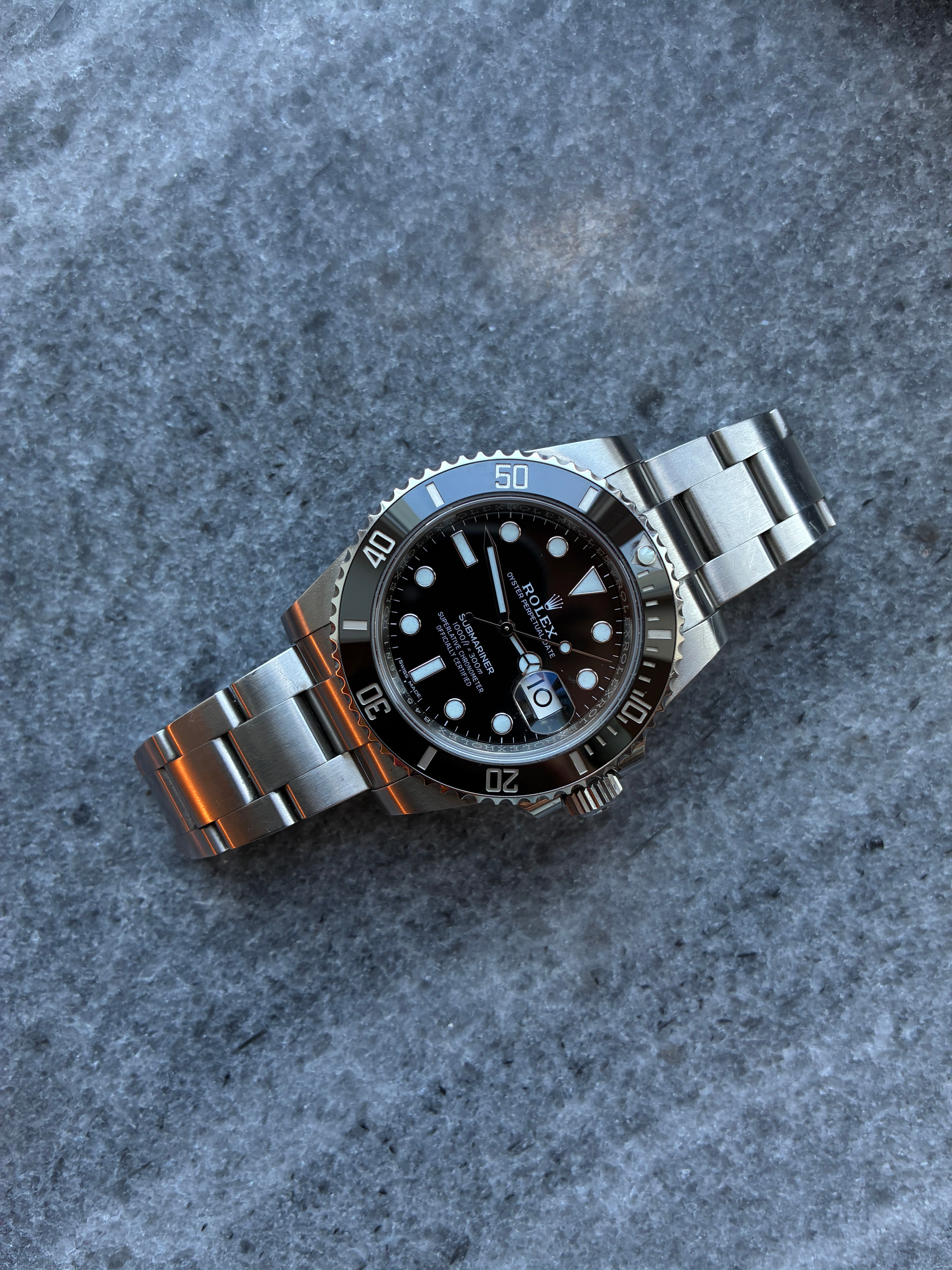 Rolex Submariner Date aus Stahl mit schwarzem Zifferblatt, im schrägen Blickwinkel auf grauem Steinboden, 2020
