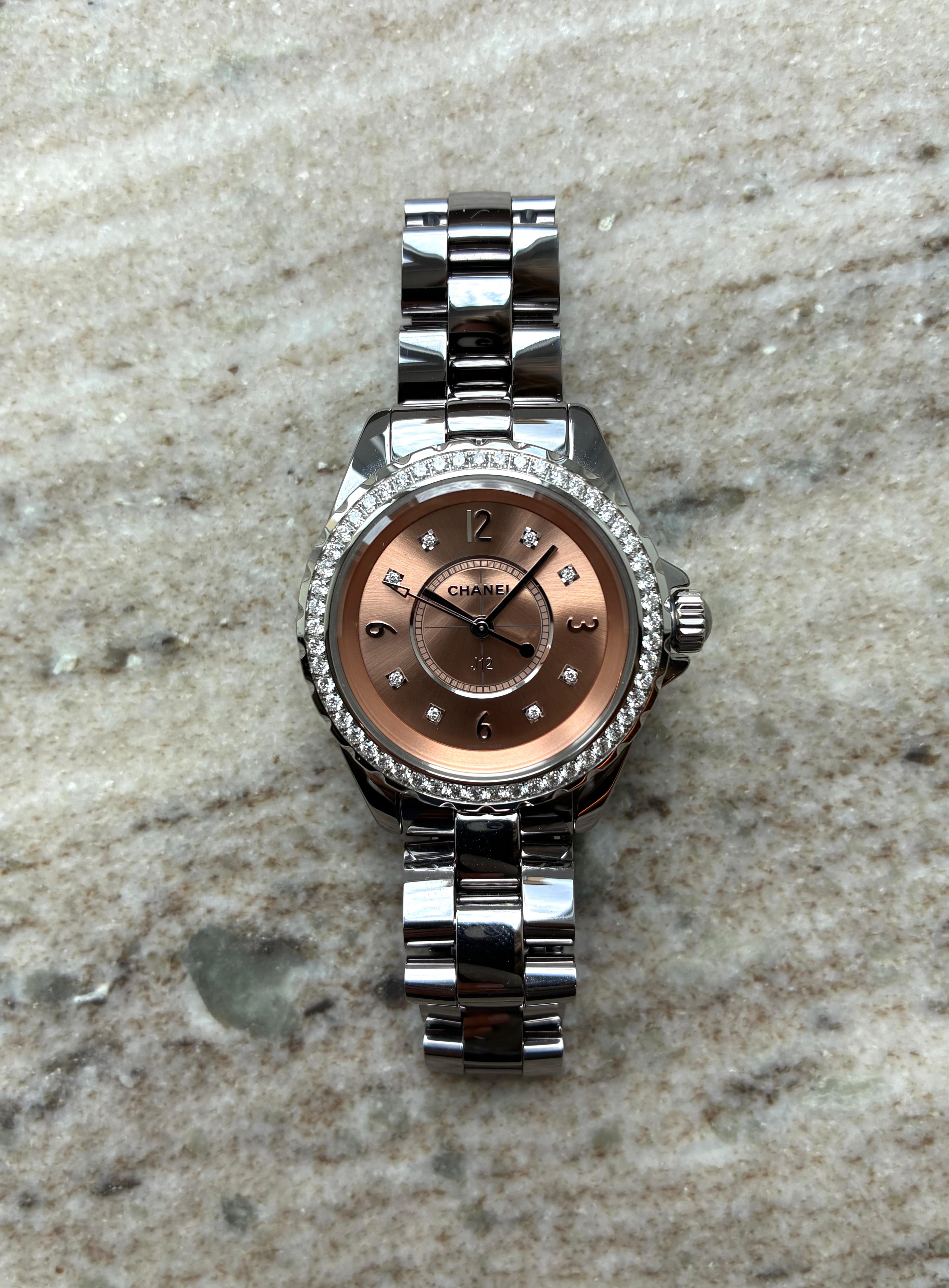 Chanel J12 33mm in Roségold mit Diamanten und Edelstahlarmband auf Marmorhintergrund