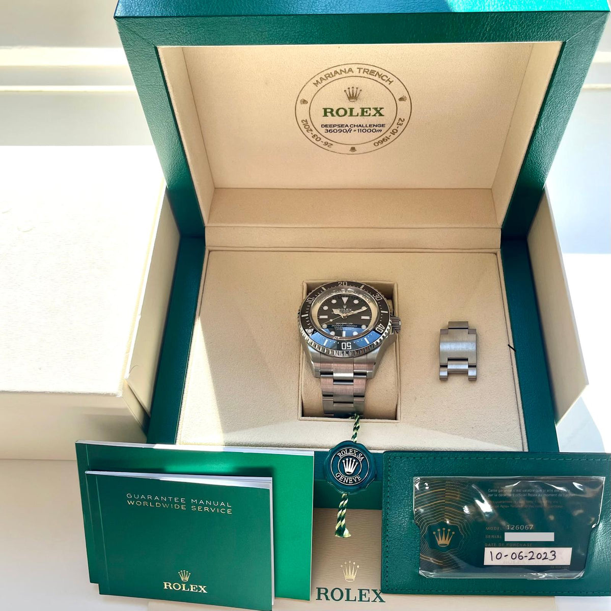 Rolex Sea-Dweller Deepsea Challenge / Unworn / Full-Set / 2023 / Sticker, Gesamtansicht mit Box, Zifferblatt und Unterlagen vor neutralem Hintergrund