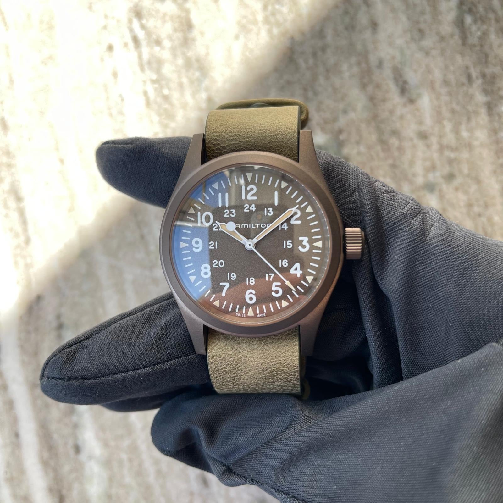 Hamilton Khaki Field Mechanical / box / certificate / like new / unworn / 2025, Vorderansicht mit Zifferblatt, Krone und Armband vor neutralem Hintergrund
