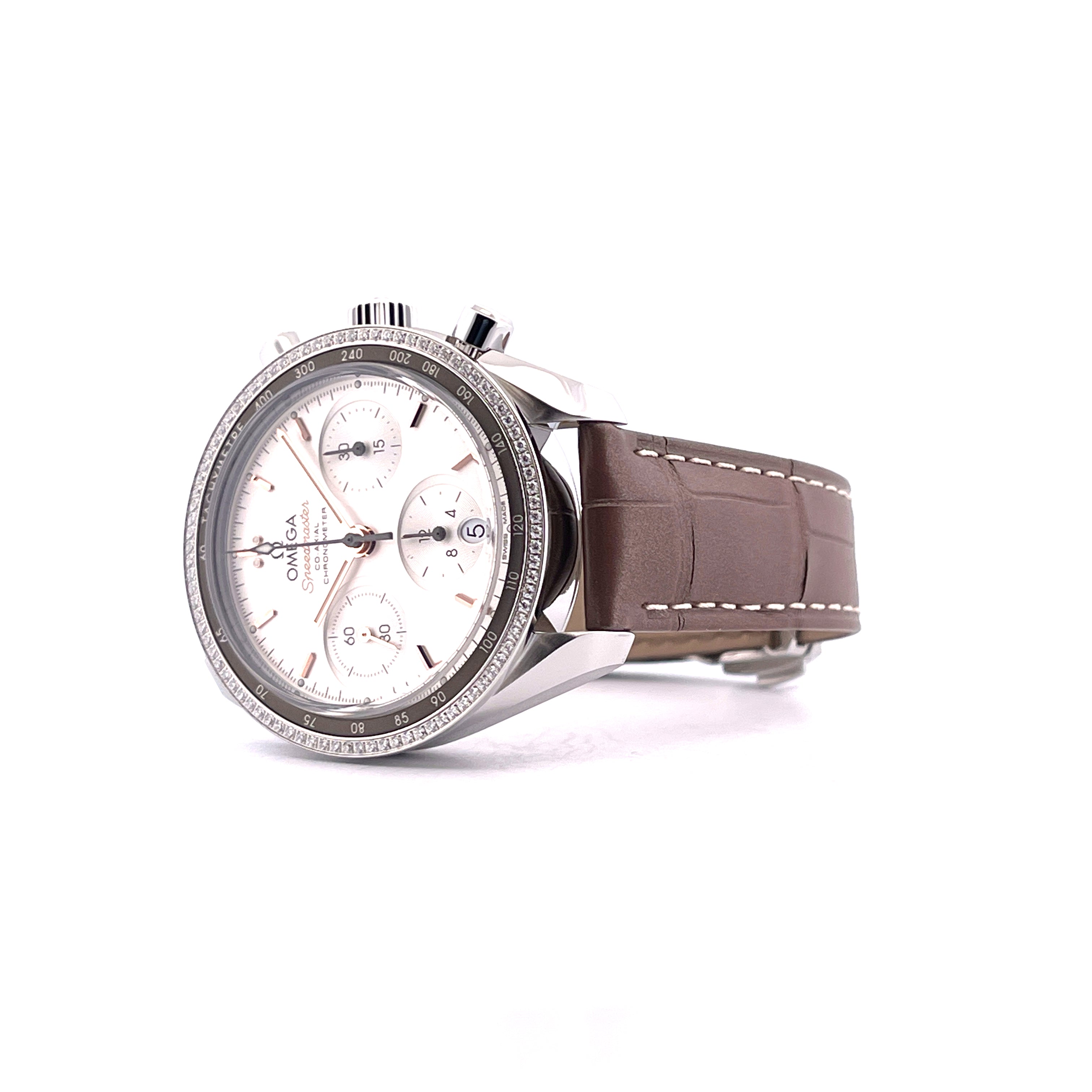 Omega Speedmaster Lady 38 mit weißem Zifferblatt, Diamantlünette und braunem Lederarmband, seitlich betrachtet auf weißem…