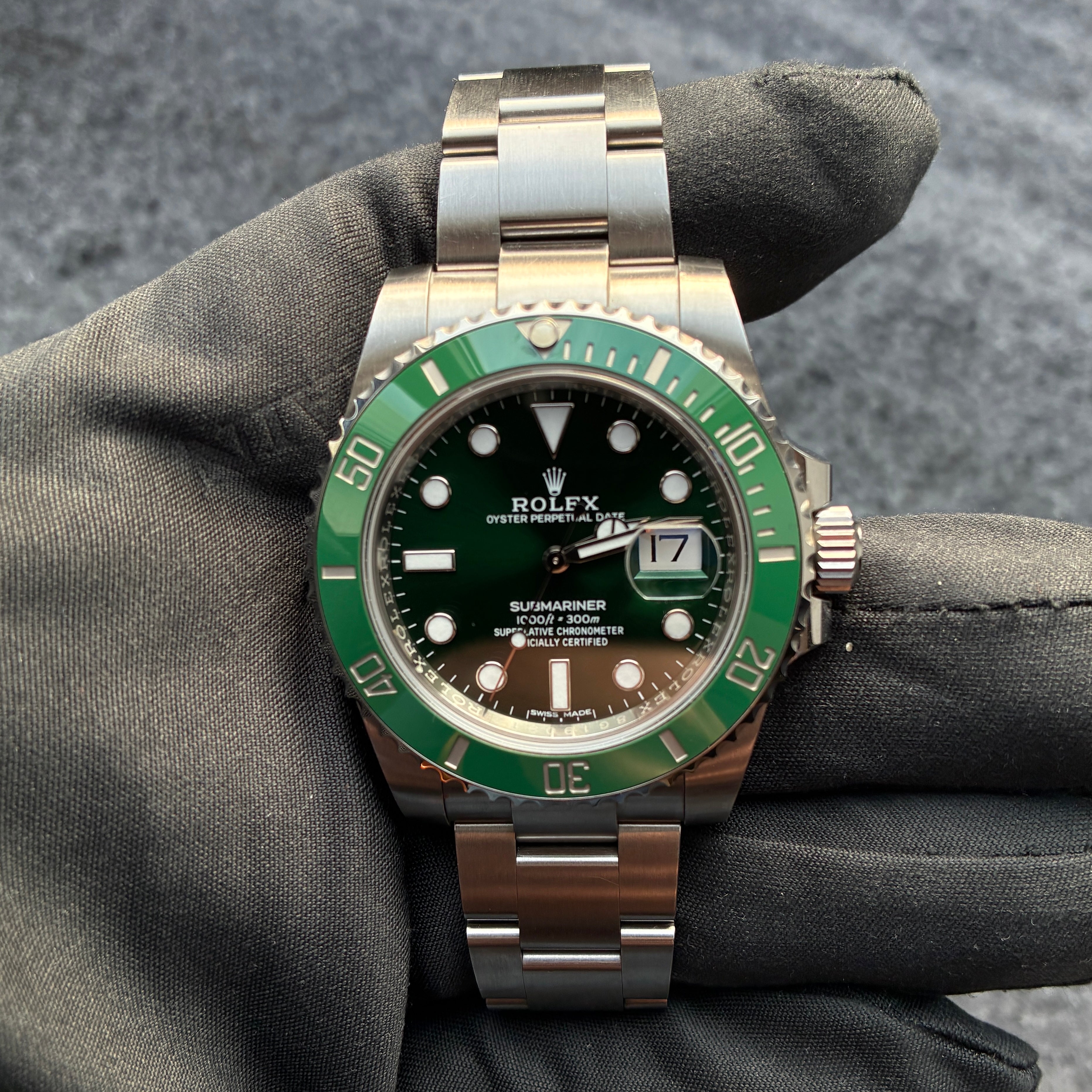 Rolex Submariner Date Hulk mit grünem Zifferblatt und Stahlband auf grauem Hintergrund